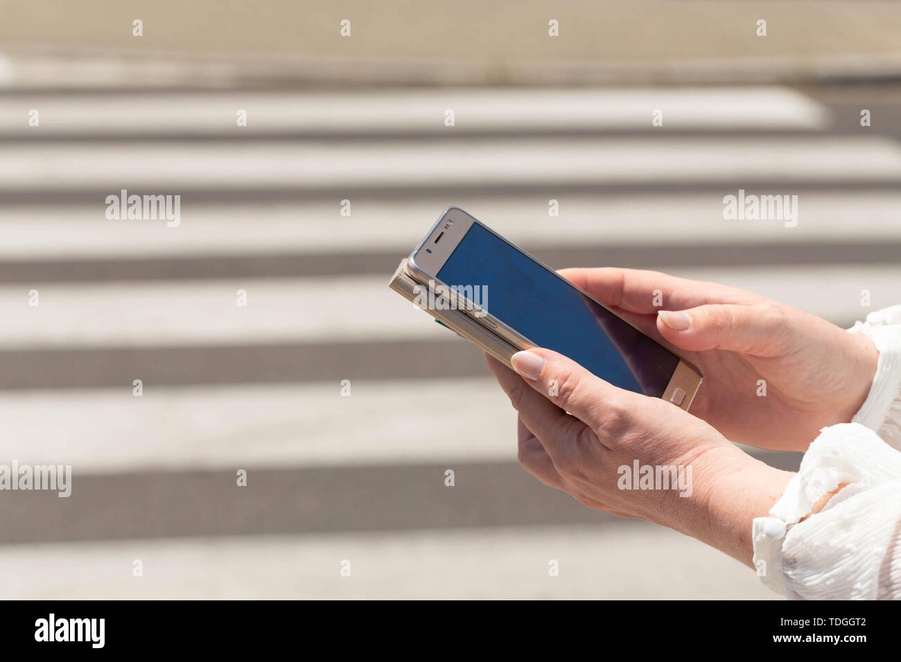 La femme, straring au téléphone, traverse les rues / concept Banque D'Images