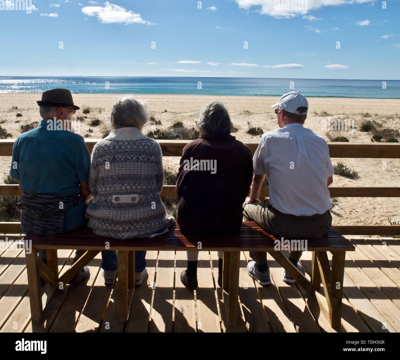 Les personnes âgées sont assis sur un banc en regardant la plage Banque D'Images