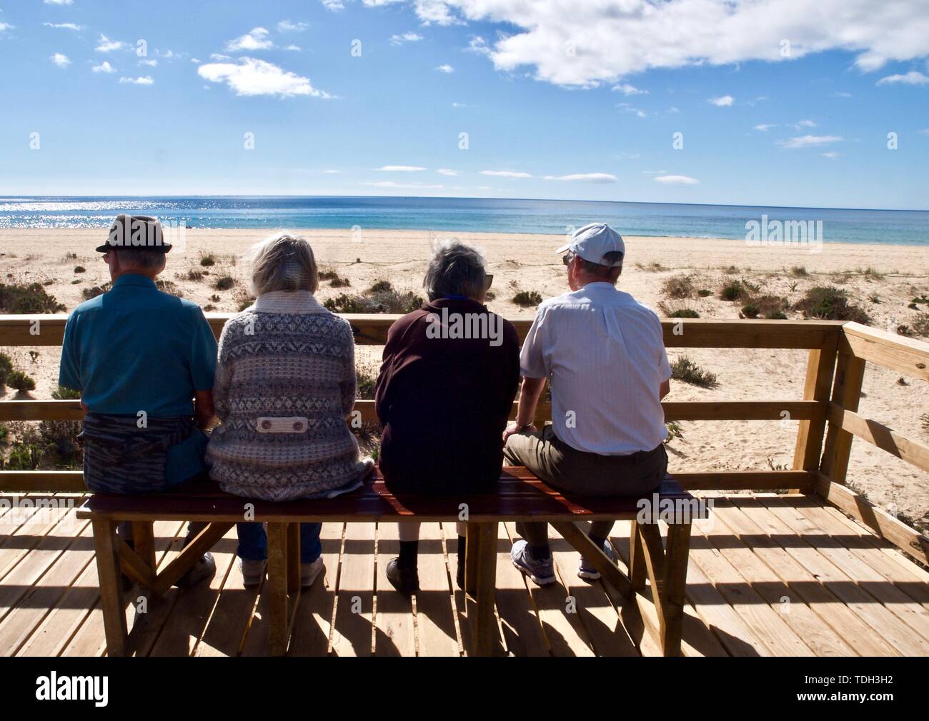 Les personnes âgées sont assis sur un banc en regardant la plage Banque D'Images