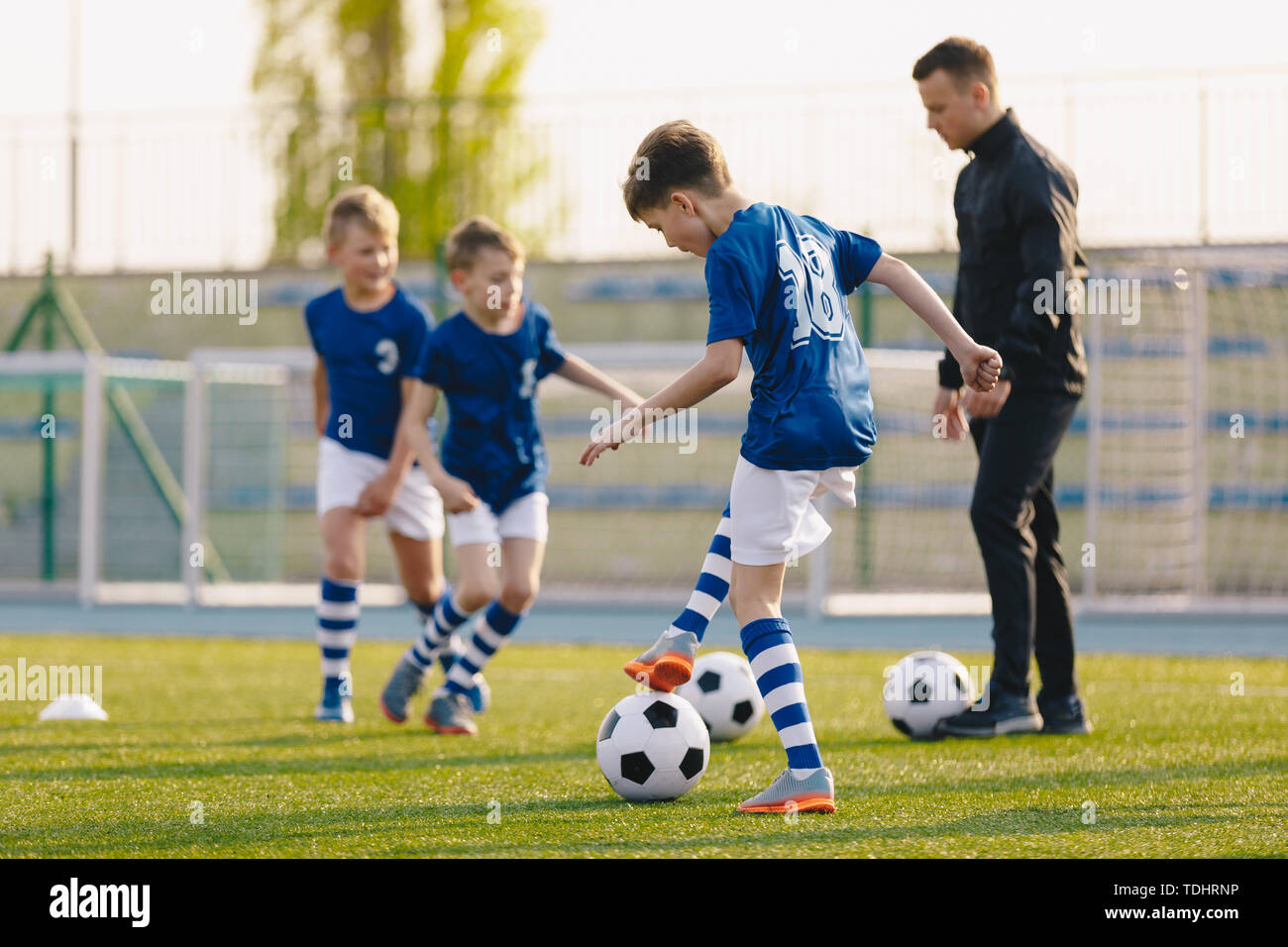 Exercices pratiques d'entraînement de football pour les jeunes joueurs de soccer. Les garçons sur la formation avec des ballons de foot sur Pitch Banque D'Images