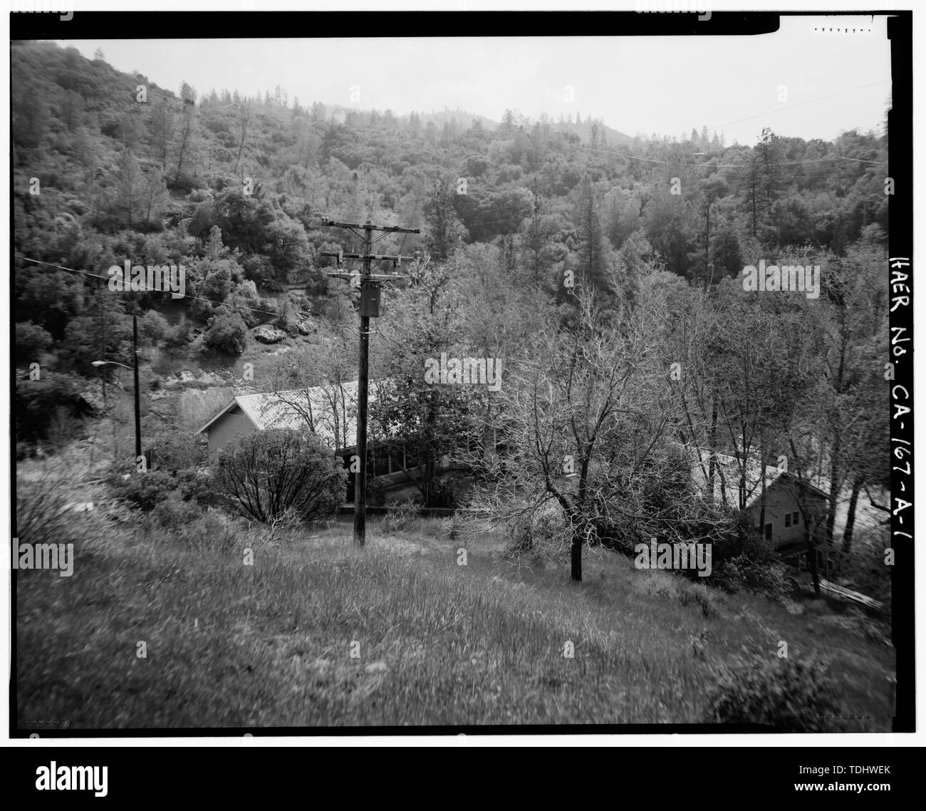 Description de l'ÉLABORATION 105 montrant réglage local. Toit, l'extrémité nord, ET CÔTÉ OUEST DE LA CONSTRUCTION 105 SONT VISIBLES AU CENTRE DE LA PHOTO DE GAUCHE DERRIÈRE POTEAU. WEST END ET TOIT DU BÂTIMENT 110 SONT VISIBLES EN PHOTO À DROITE DERRIÈRE LES ARBRES. Vue de SUD DE RUE AU-DESSUS DES MAISONS. - Système Hydroélectrique de Big Creek, le Powerhouse 8 opérateur, Cottage, le ruisseau Big, Big Creek, comté de Fresno, CA Banque D'Images