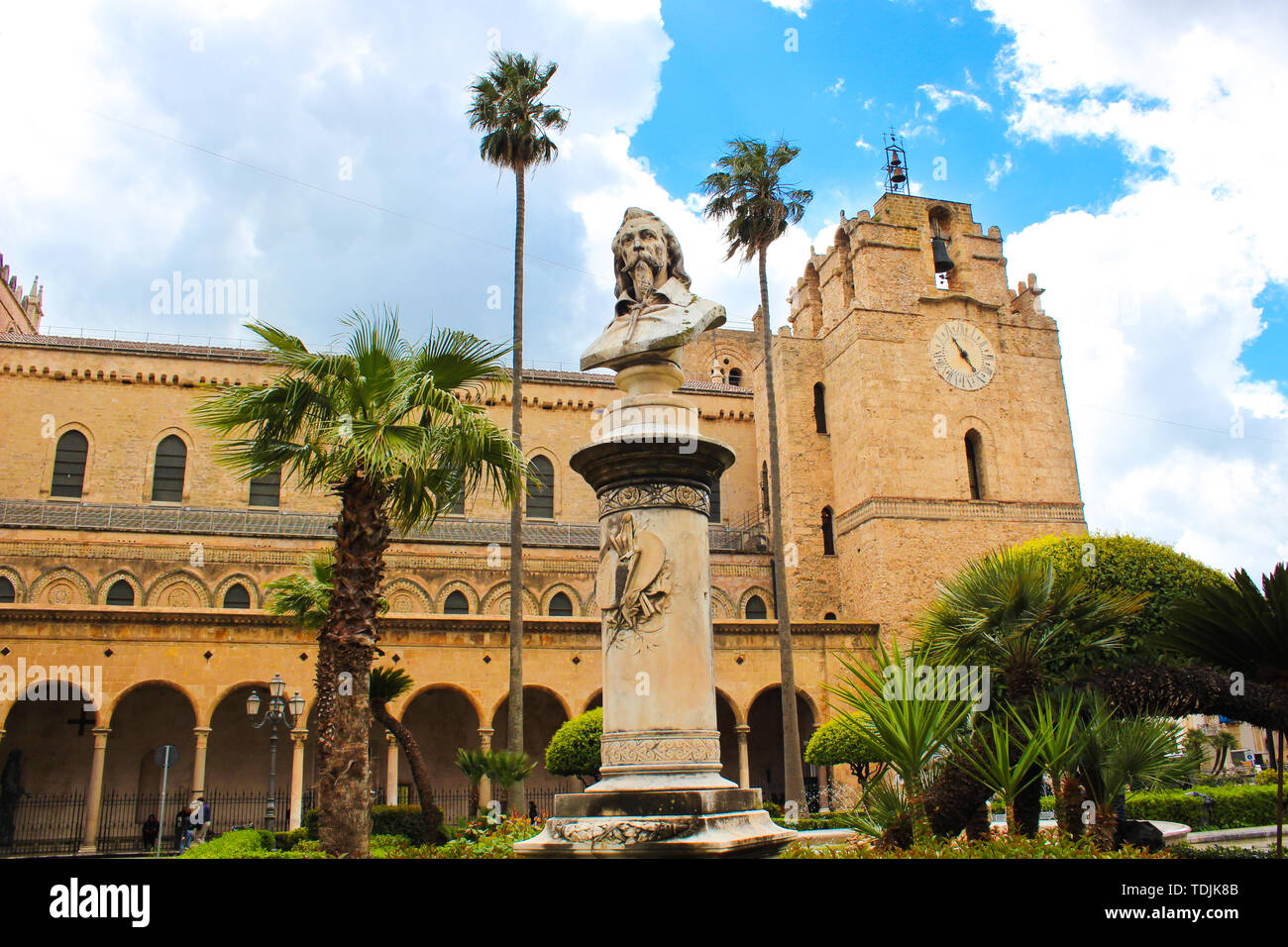 Monreale, Sicile, Italie - 11 avril 2019 - Cathédrale historique de Monreale, Duomo di Monreale extérieur avec buste du peintre Pietro Novelli. Palmiers, de nuages pendant la journée. Architecture Normande. Banque D'Images