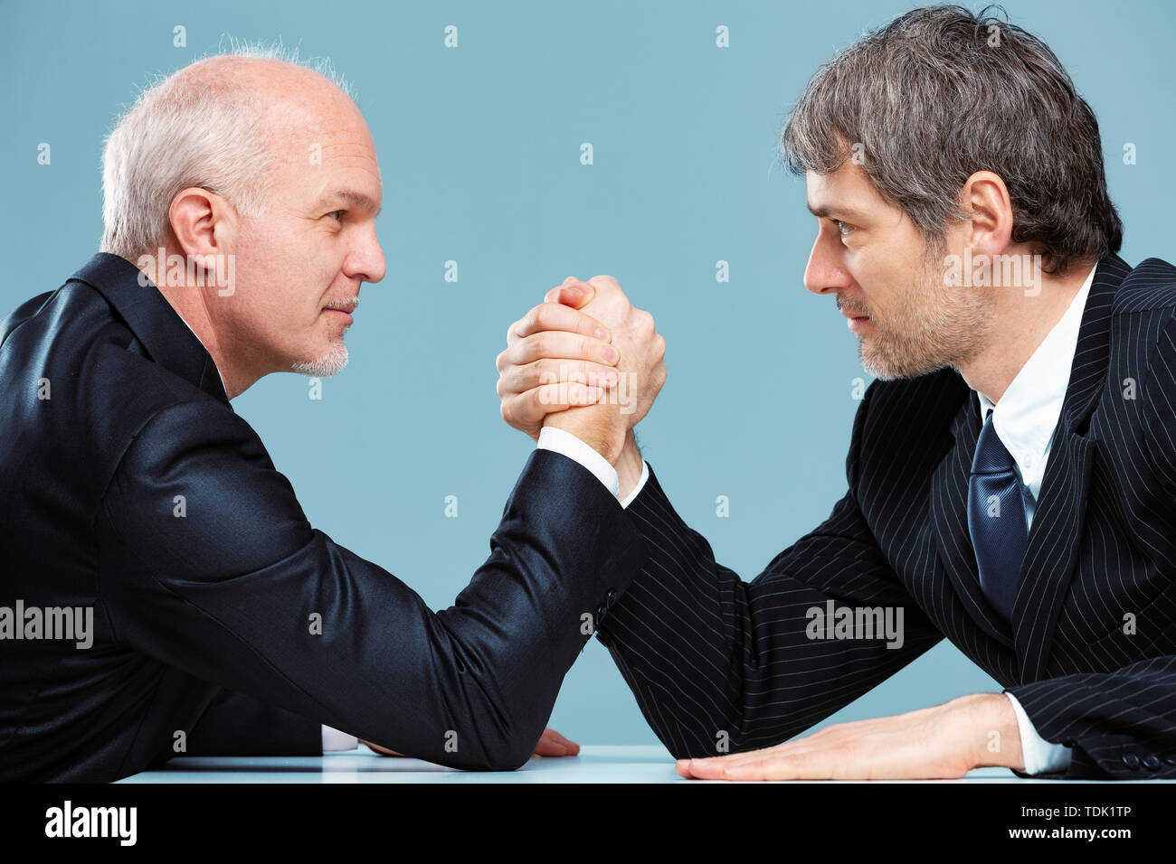 Deux hommes d'affaires auxquels les uns contre les autres dans un défi pour la suprématie Arm wrestling sur une table de bureau avec l'air de détermination dans un proche u Banque D'Images