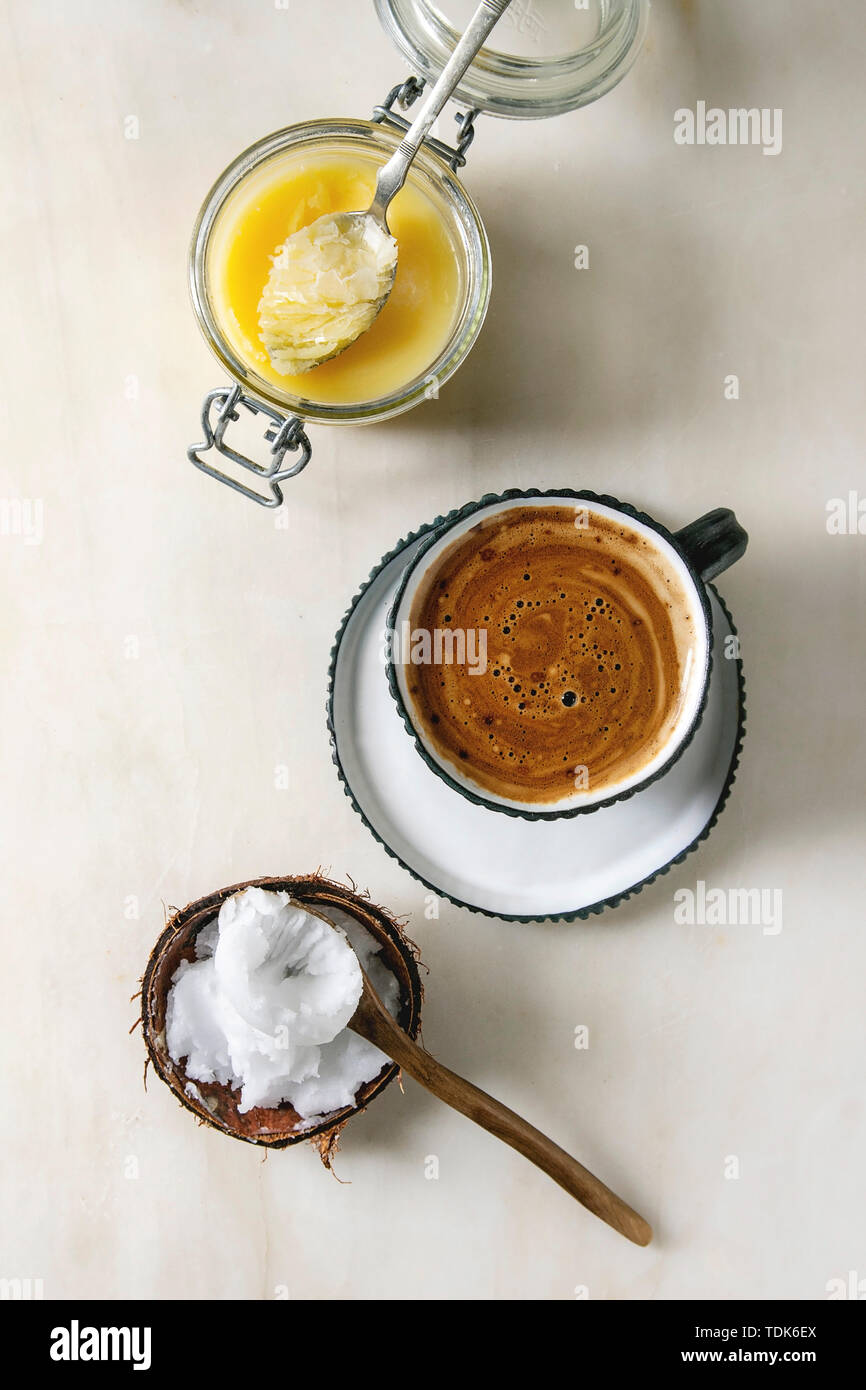 Café à toute épreuve. Diète cétonique en bleu café tasse en céramique avec le beurre de coco bio ghee et l'huile de pression à froid dans les cuillères sur fond de marbre blanc. F Banque D'Images