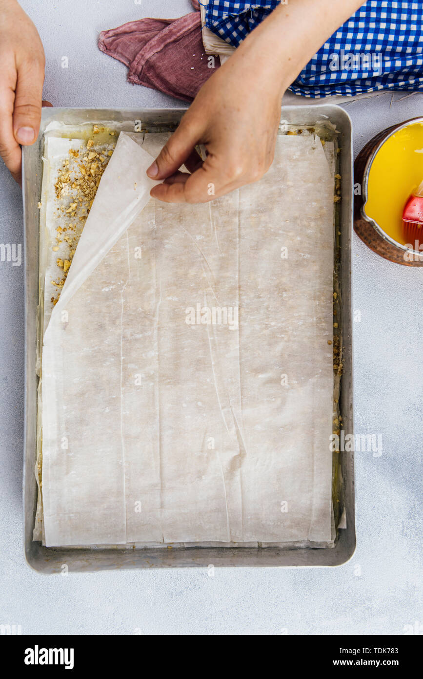 Woman making baklava couches avec des feuilles de pâte filo sur une plaque à pâtisserie Banque D'Images