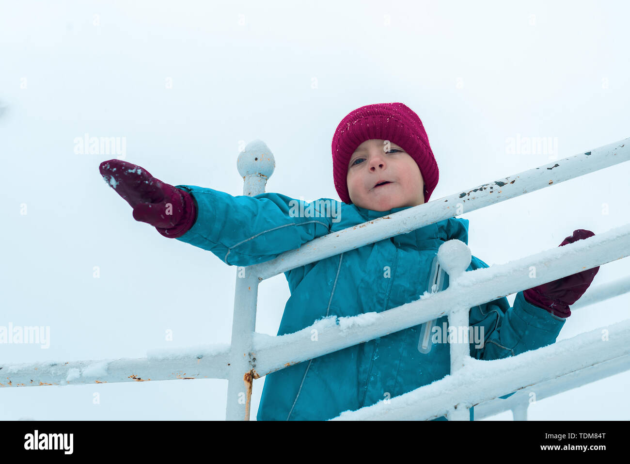 L'hiver portrait of a cute boy en Bourgogne. chapeau et gants enfant émotionnel de jouer et en agitant les bras Banque D'Images