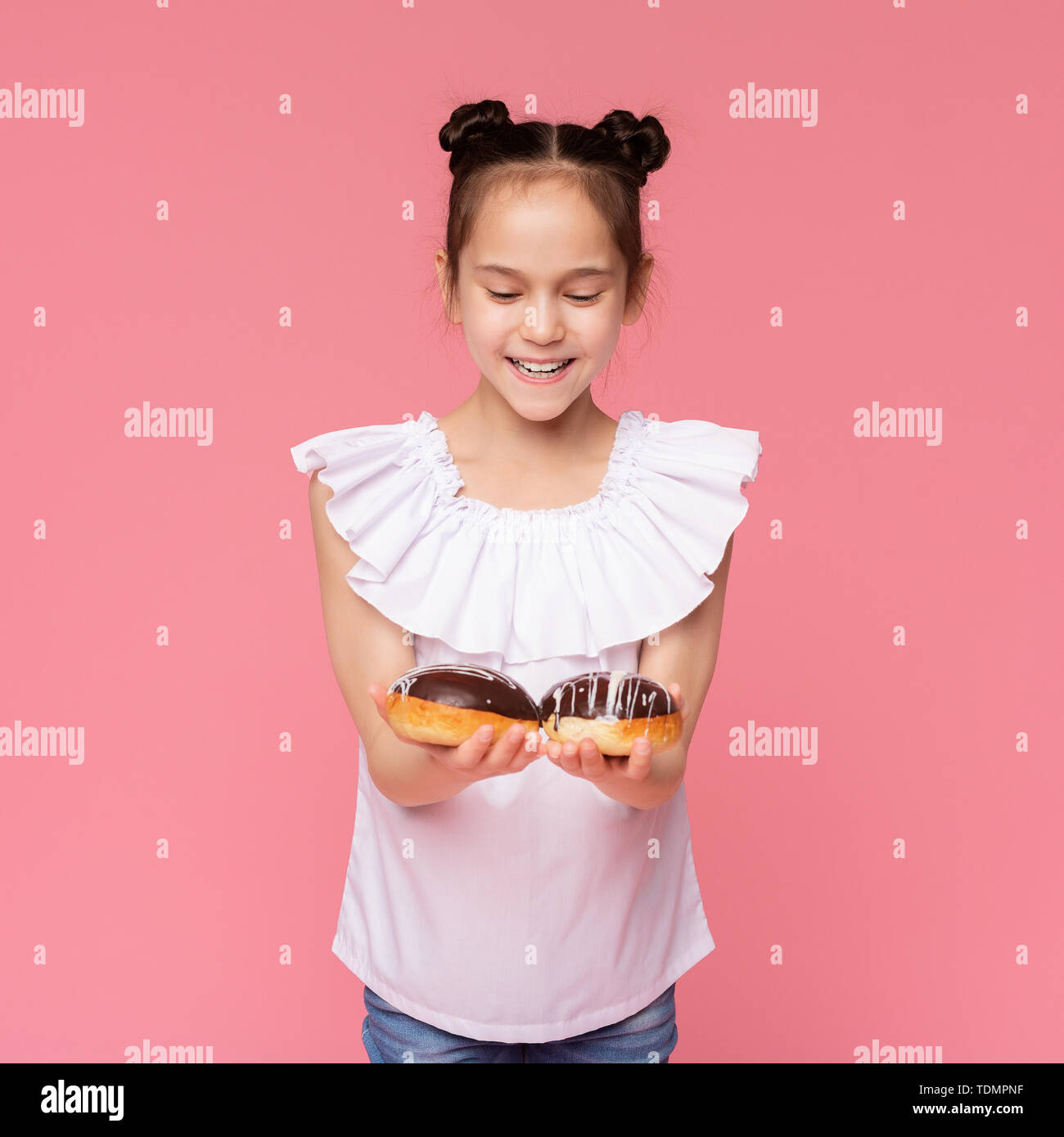 Petite fille joyeuse profitant des beignets au chocolat Banque D'Images