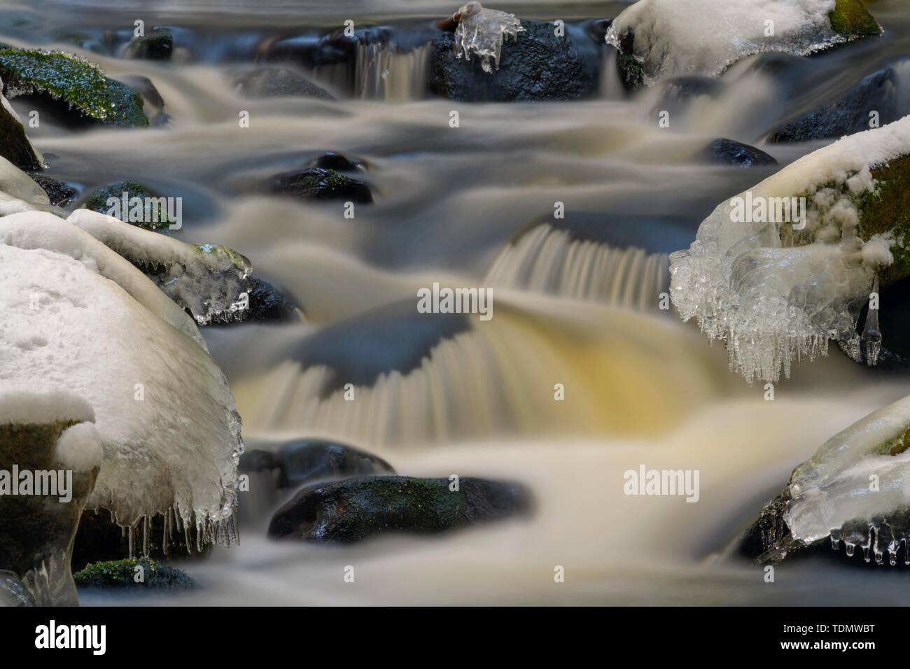 Fleuve sauvage avec de la glace et des pierres couvertes de neige en hiver, Hammerbach, longue exposition, Parc National de Sumava, forêt de Bohême, République Tchèque Banque D'Images