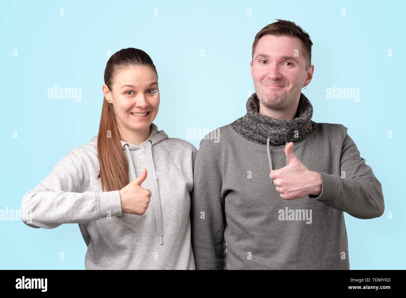 Happy young couple showing thumb up sur fond bleu. Banque D'Images