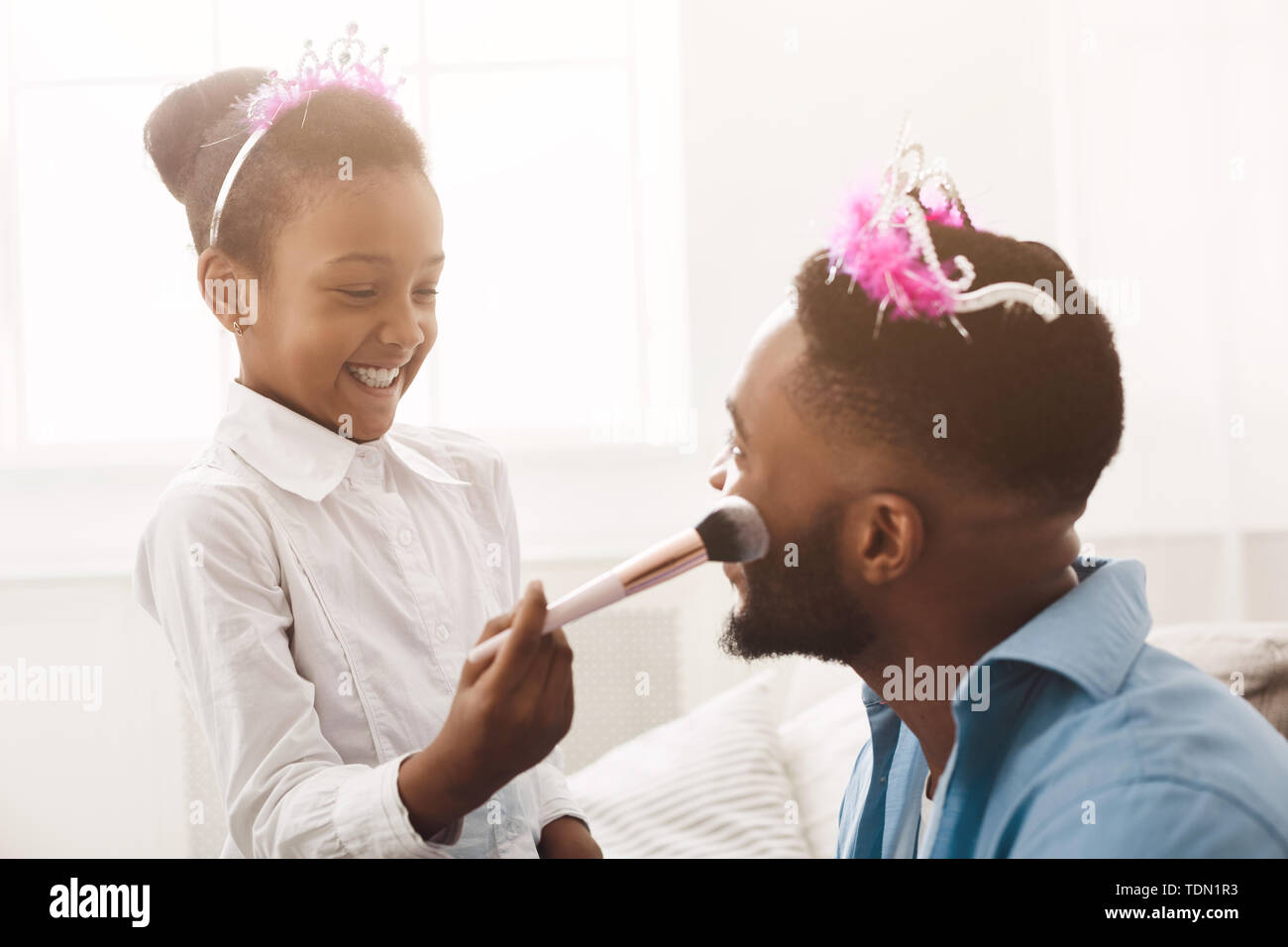 Petite fille de faire un miroir de son père, portant des couronnes Banque D'Images