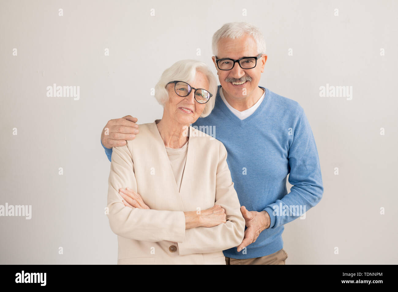 Affectionate couple senior dans smart casualwear vous regarde en se tenant debout en face de la caméra dans l'isolement Banque D'Images
