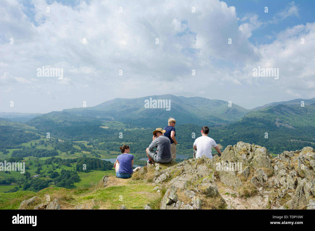 Les gens se reposant au sommet de Loughrigg est tombé dans le Parc National de Lake District avec Wetherlam dans la distance. Cumbria, Angleterre. Banque D'Images