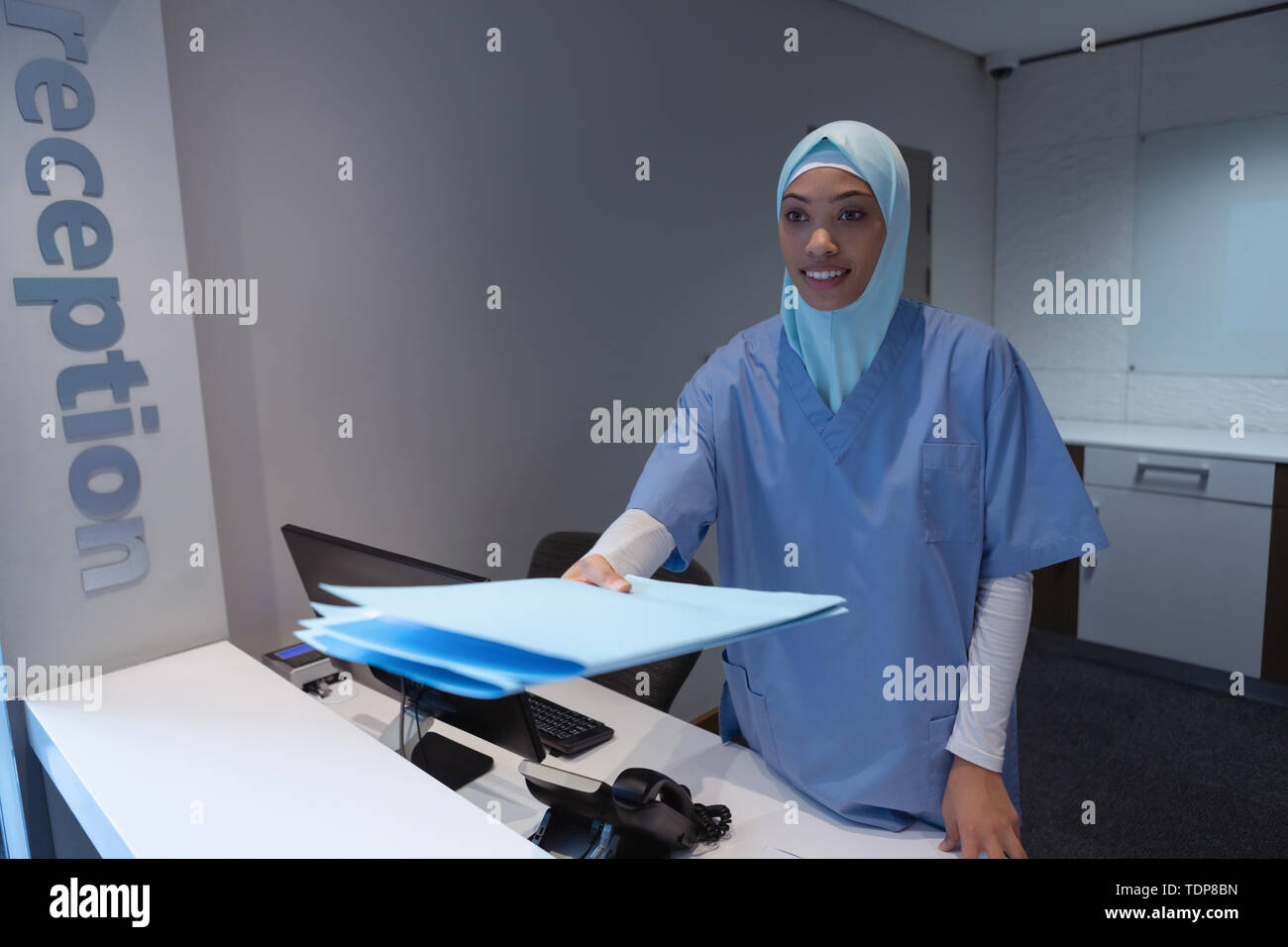 Chirurgienne en hijab avec commandes à la réception du fichier de rapport médical à l'hôpital Banque D'Images