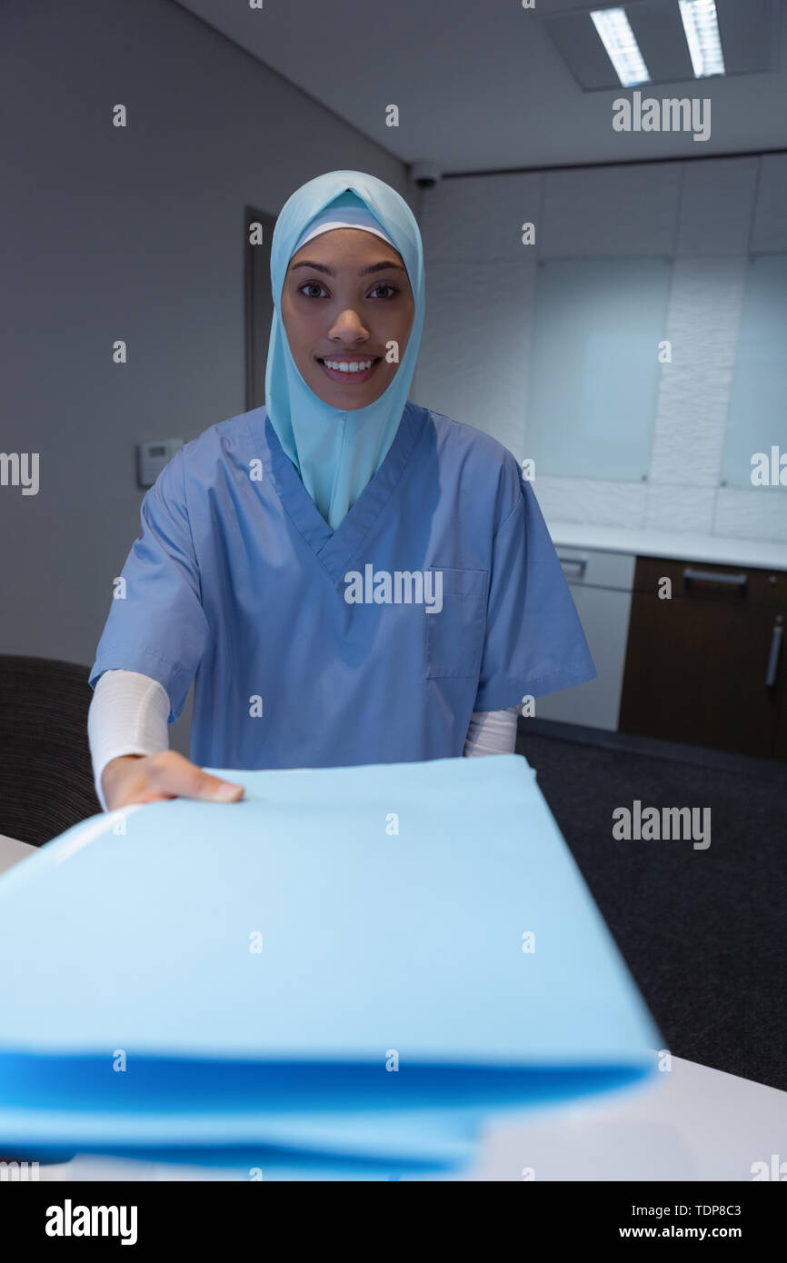 Chirurgienne en hijab avec commandes à la réception du fichier de rapport médical à l'hôpital Banque D'Images