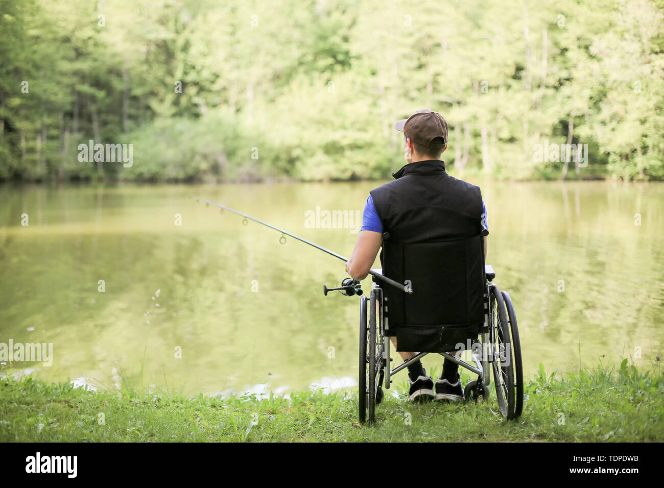 Professionnels et jeunes handicapés à un lac à la pêche l'homme dans la nature. Sport populaire pour paraplégiques. Banque D'Images