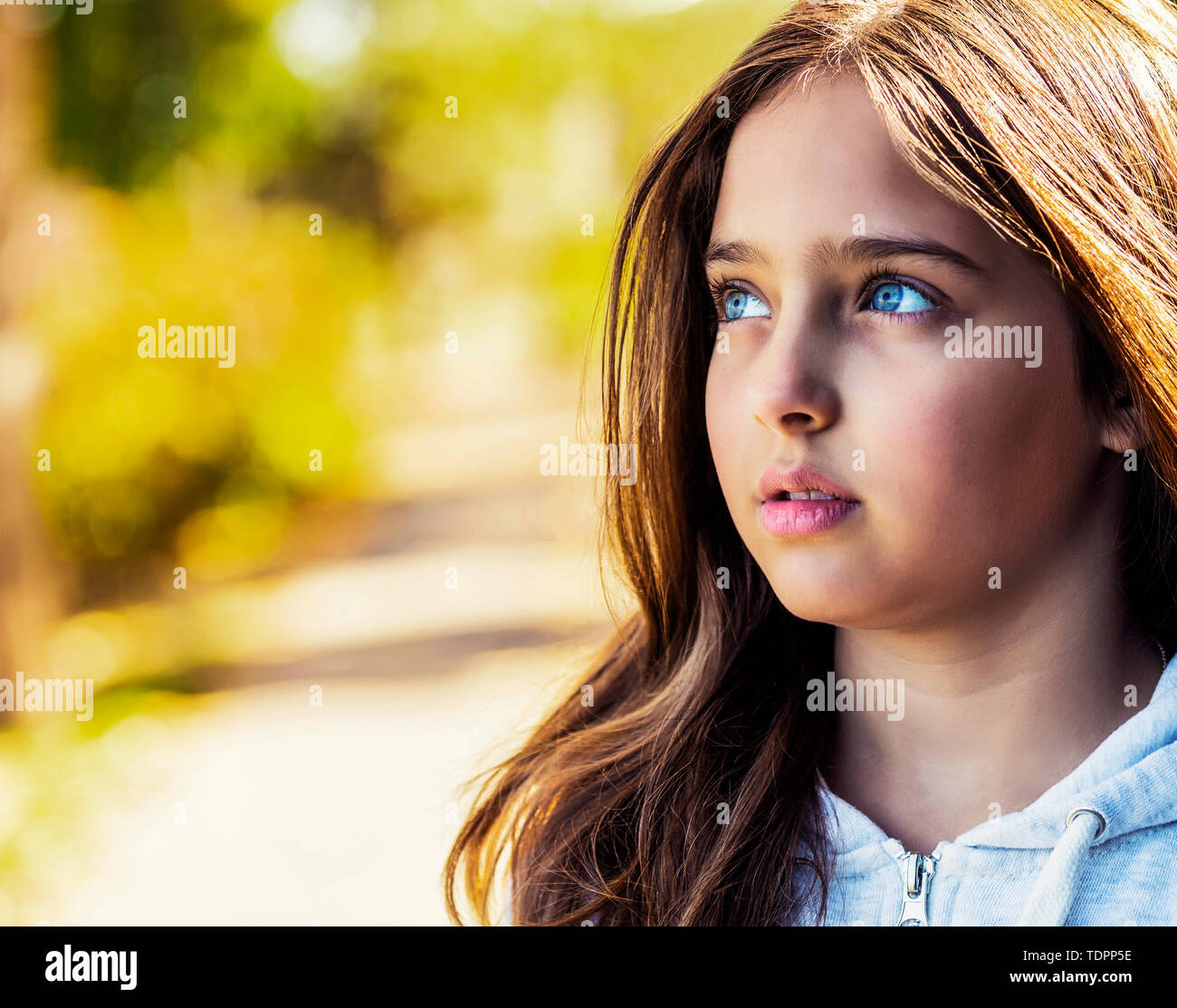 Une jeune fille en pleine réflexion tout en regardant vers le haut sur une chaude journée d'automne dans un parc de la ville ; Edmonton, Alberta, Canada Banque D'Images