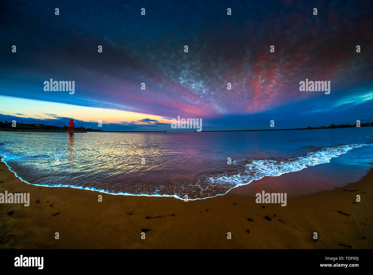 Épi de troupeau phare et orange avec des nuages lumineux et tide lave sur plage à l'avant-plan ; à South Shields, Tyne and Wear, England Banque D'Images