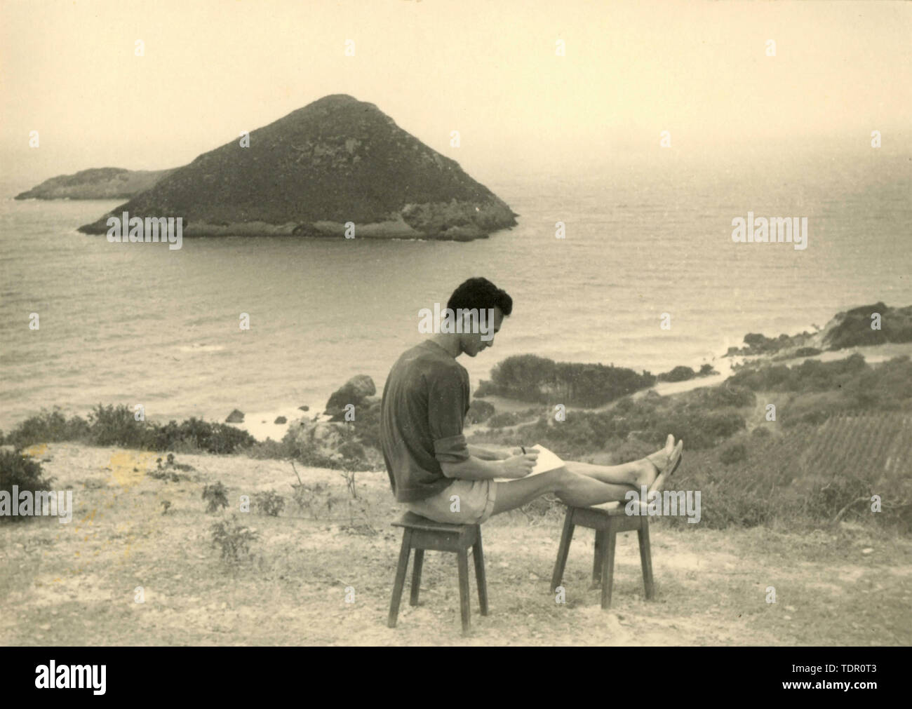 L'homme écrit un poème en face de la mer, Italie 1960 Banque D'Images