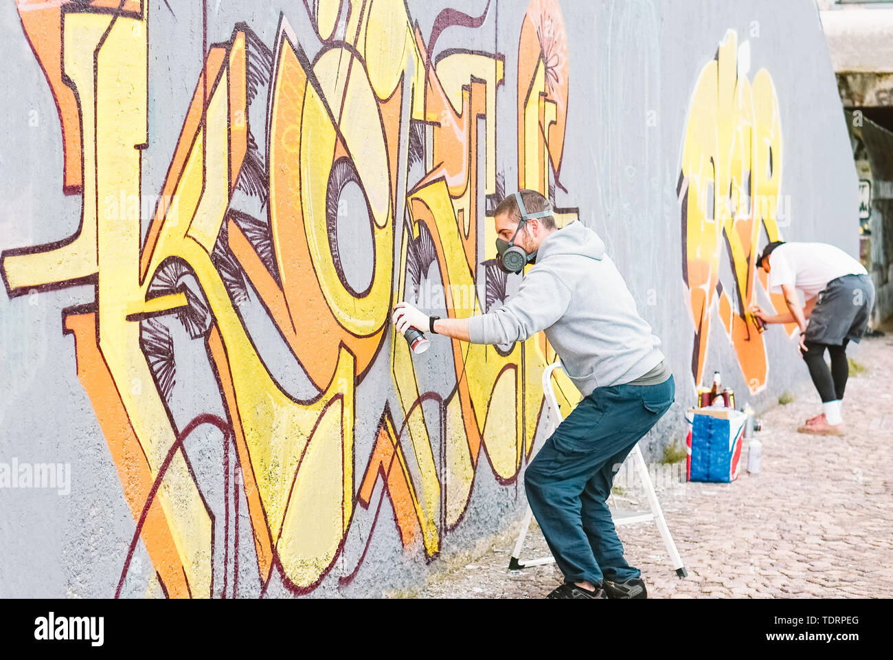 Les artistes graffiti peinture murale colorée sur un mur gris hommes créatifs - L'exécution de peintures murales de dessin Banque D'Images