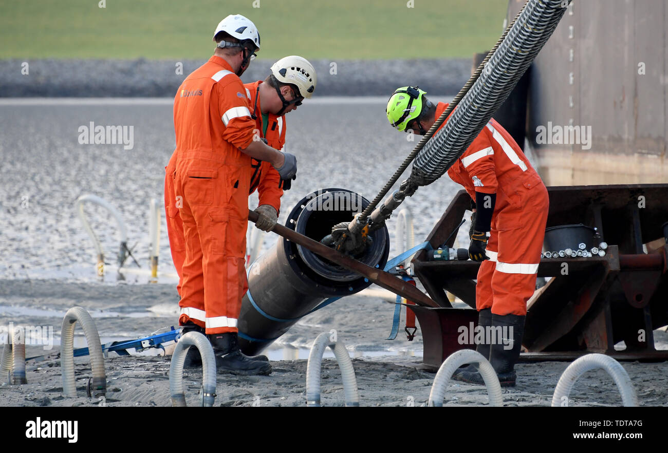 19 juin 2019, le Schleswig-Holstein, Büsum : La fin d'un câble sous-marin 516 kilomètre de long est ramené à terre par un navire de la pose de câbles dans les vasières en vertu de la digue. NordLink est le nom de la ligne électrique que pour la première fois va se connecter directement les marchés de l'électricité de l'Allemagne et la Norvège et servira d'échange entre l'allemand et de l'énergie éolienne l'énergie hydraulique norvégien. D'ici la fin de 2019, le travail final aurait dû être terminée. Photo : Carsten Rehder/dpa Banque D'Images