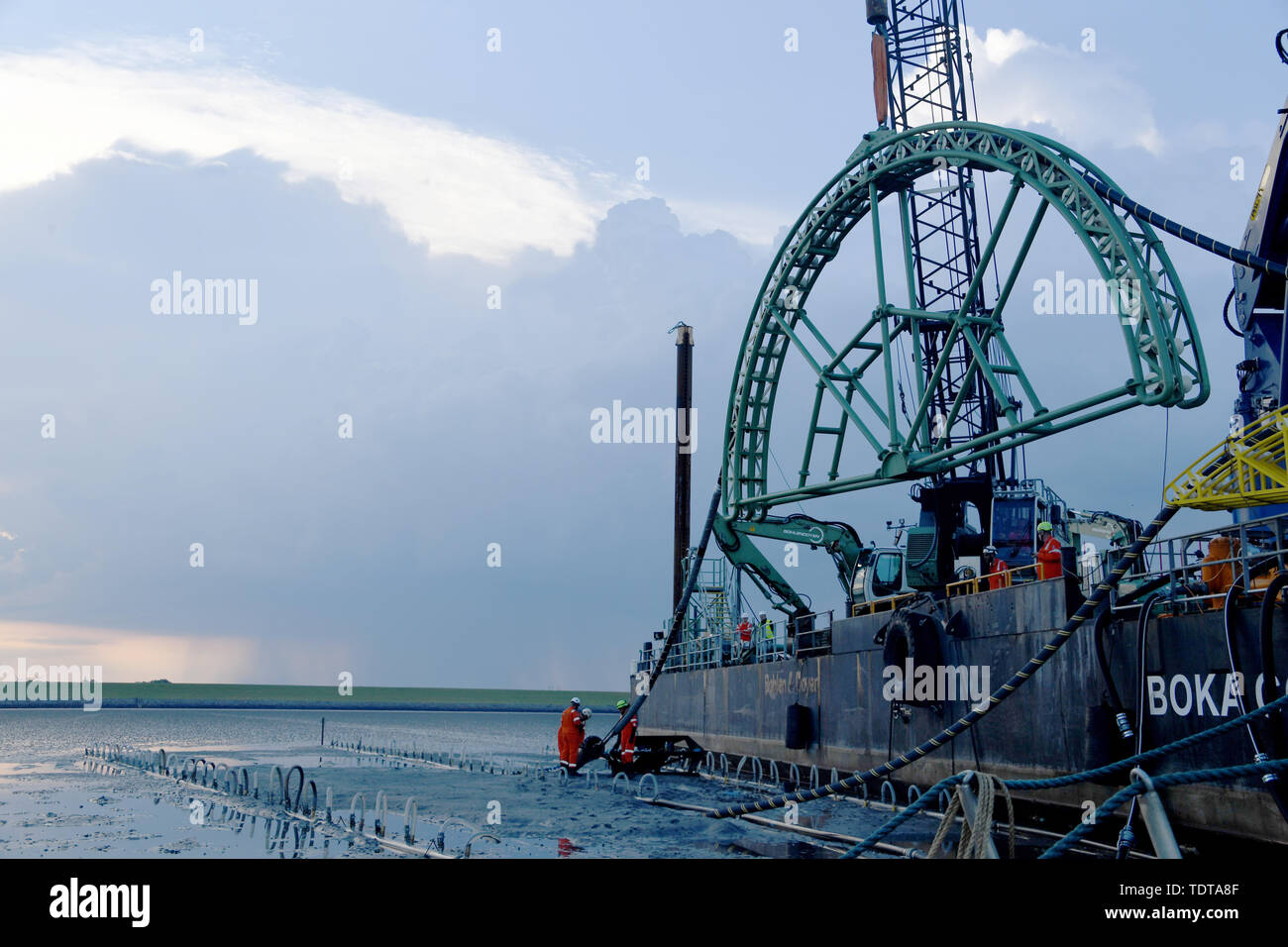 19 juin 2019, le Schleswig-Holstein, Büsum : La fin d'un câble sous-marin 516 kilomètre de long est tiré à terre par le navire câblier "Connecteur Boka' dans la boue sous la digue. NordLink est le nom de la ligne électrique que pour la première fois va se connecter directement les marchés de l'électricité de l'Allemagne et la Norvège et servira d'échange entre l'allemand et de l'énergie éolienne l'énergie hydraulique norvégien. D'ici la fin de 2019, le travail final aurait dû être terminée. Photo : Carsten Rehder/dpa Banque D'Images