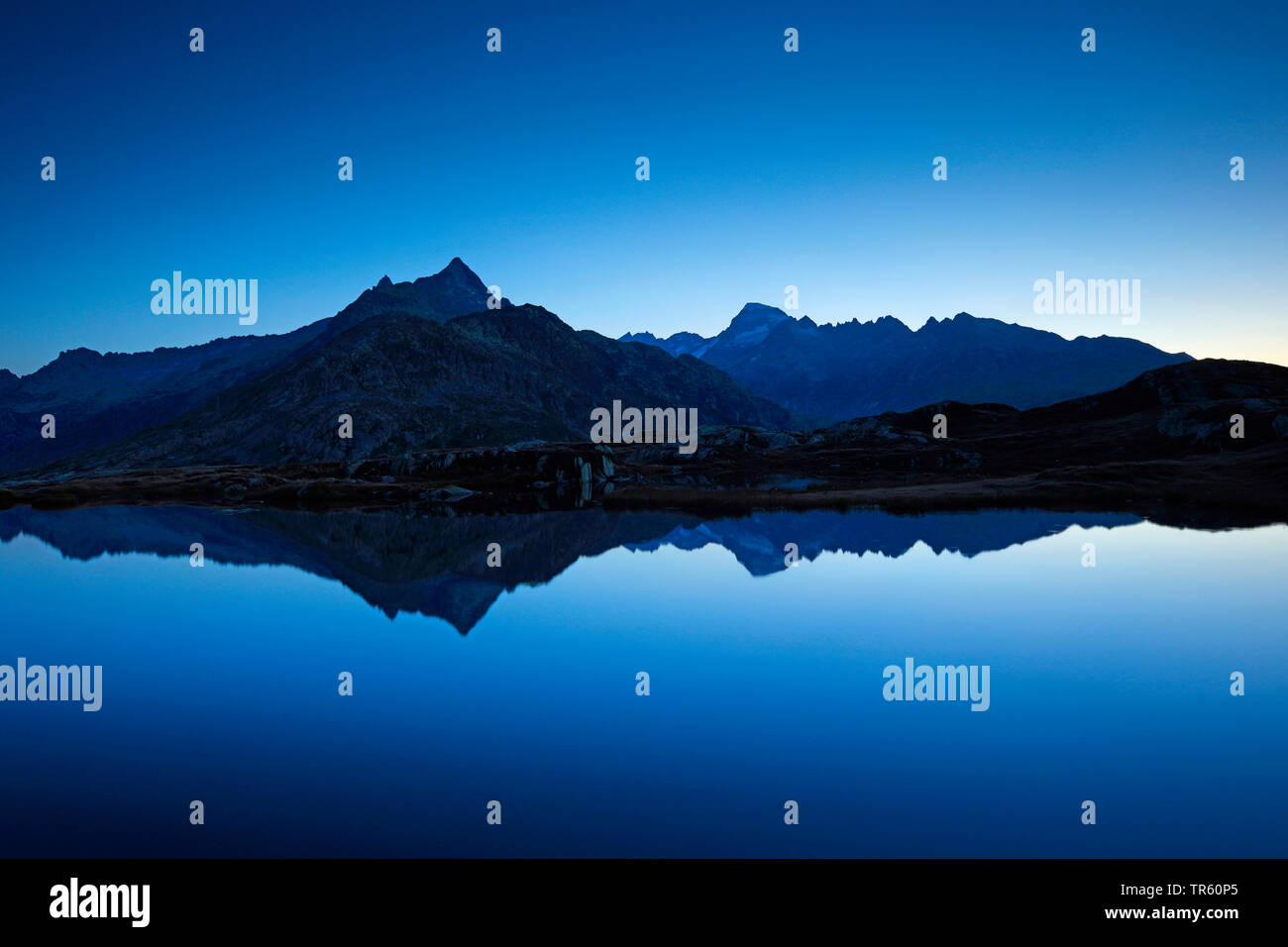 Gaerstenhoerner et montagnes Galenstock miroir dans un lac de montagne tôt le matin, Suisse Banque D'Images