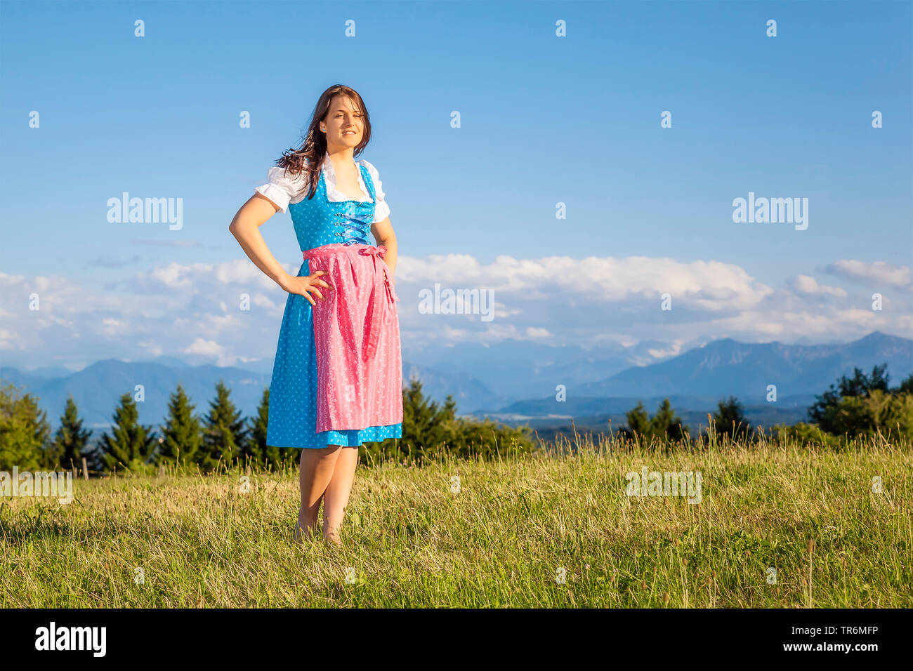 Jeune femme en dirndl debout sur une prairie de montagne, l'Allemagne, la Bavière Banque D'Images