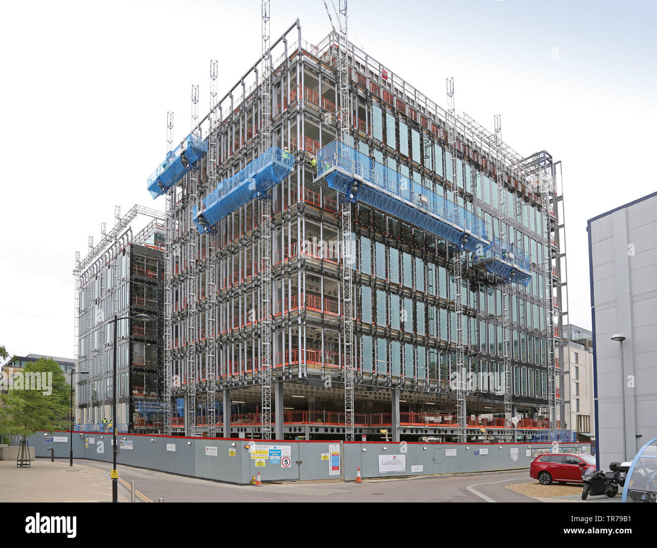 L'escalade du mât électrique plates-formes d'accès à utiliser pour la décoration d'un nouveau bâtiment de bureaux à Cambridge's Station Plazza le développement. UK Banque D'Images