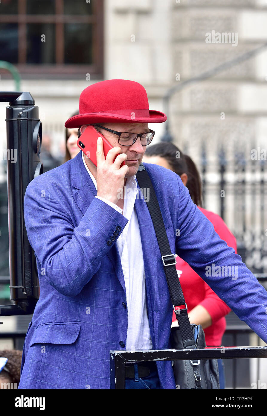 Londres, Angleterre, Royaume-Uni. Homme dans un chapeau melon rouge rouge à l'aide d'un téléphone mobile dans Whitehall Banque D'Images