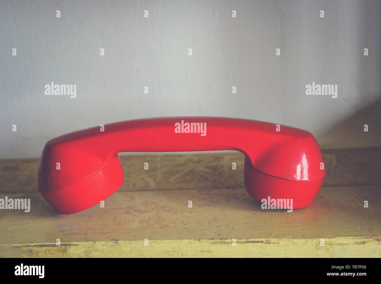 Téléphone rétro rouge / récepteur téléphonique rouge vieille table en bois dans un style ancien bureau Banque D'Images