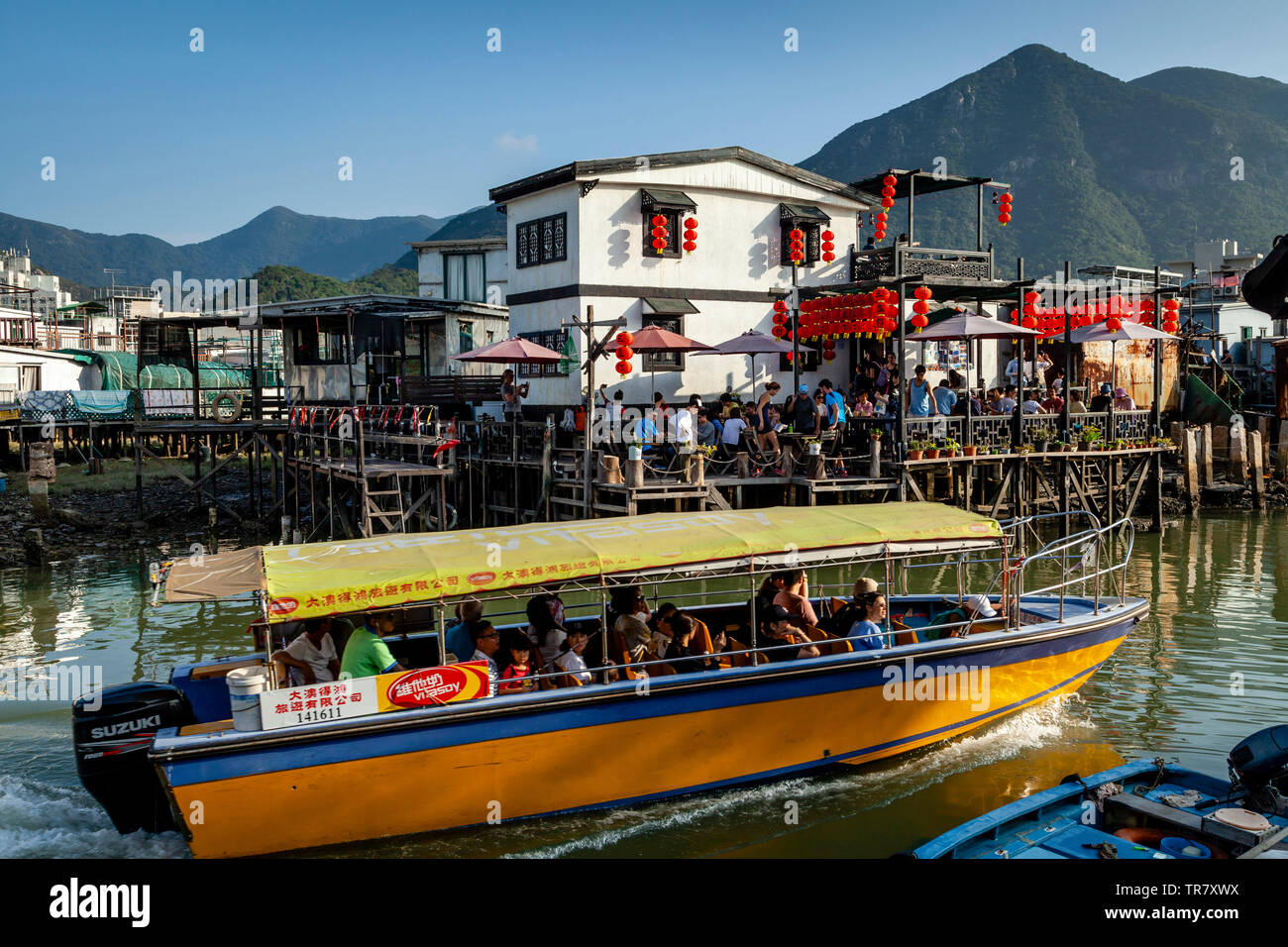 Un voyage en bateau touristique passe d'un restaurant sur pilotis, village de pêcheurs Tai O, Hong Kong, Chine Banque D'Images