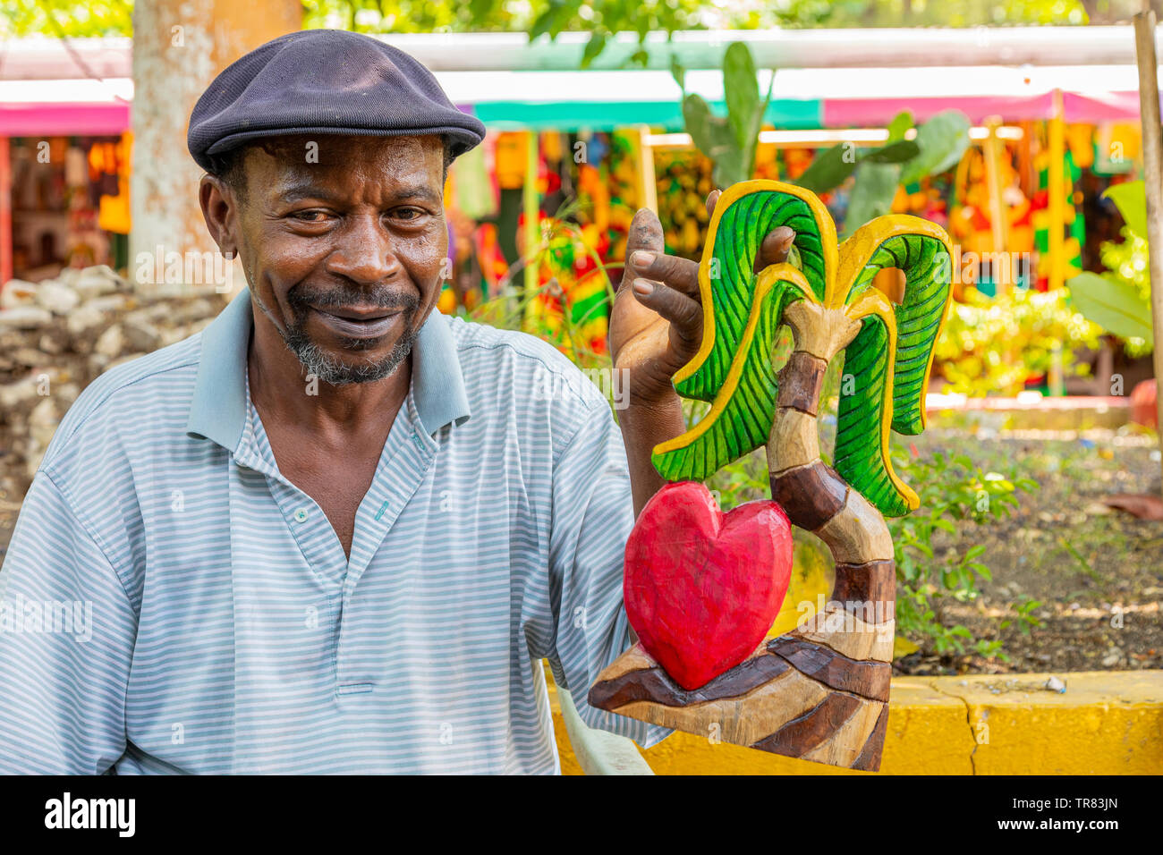 La tenue d'un commerçant local les sculptures en bois qu'il a fait pour vendre aux touristes à un marché d'artisanat local, Ocho Rios, Jamaïque, Caraïbes Banque D'Images