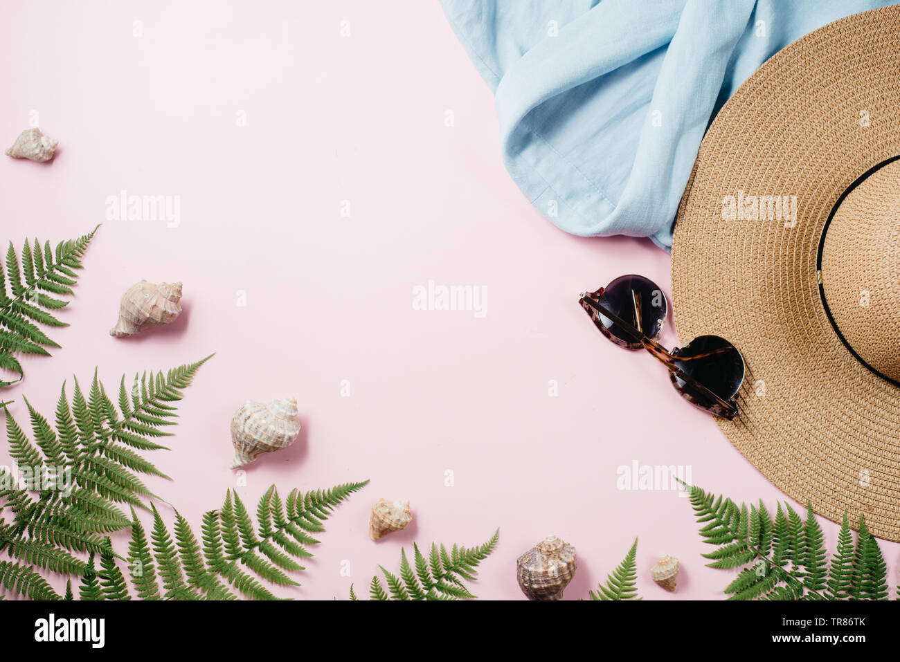 @Summer mode féminine composition avec un chemisier, chapeau, lunettes, fougère, seashell sur fond rose. Mise à plat, vue du dessus des vêtements minimalistes collage. Tr Banque D'Images
