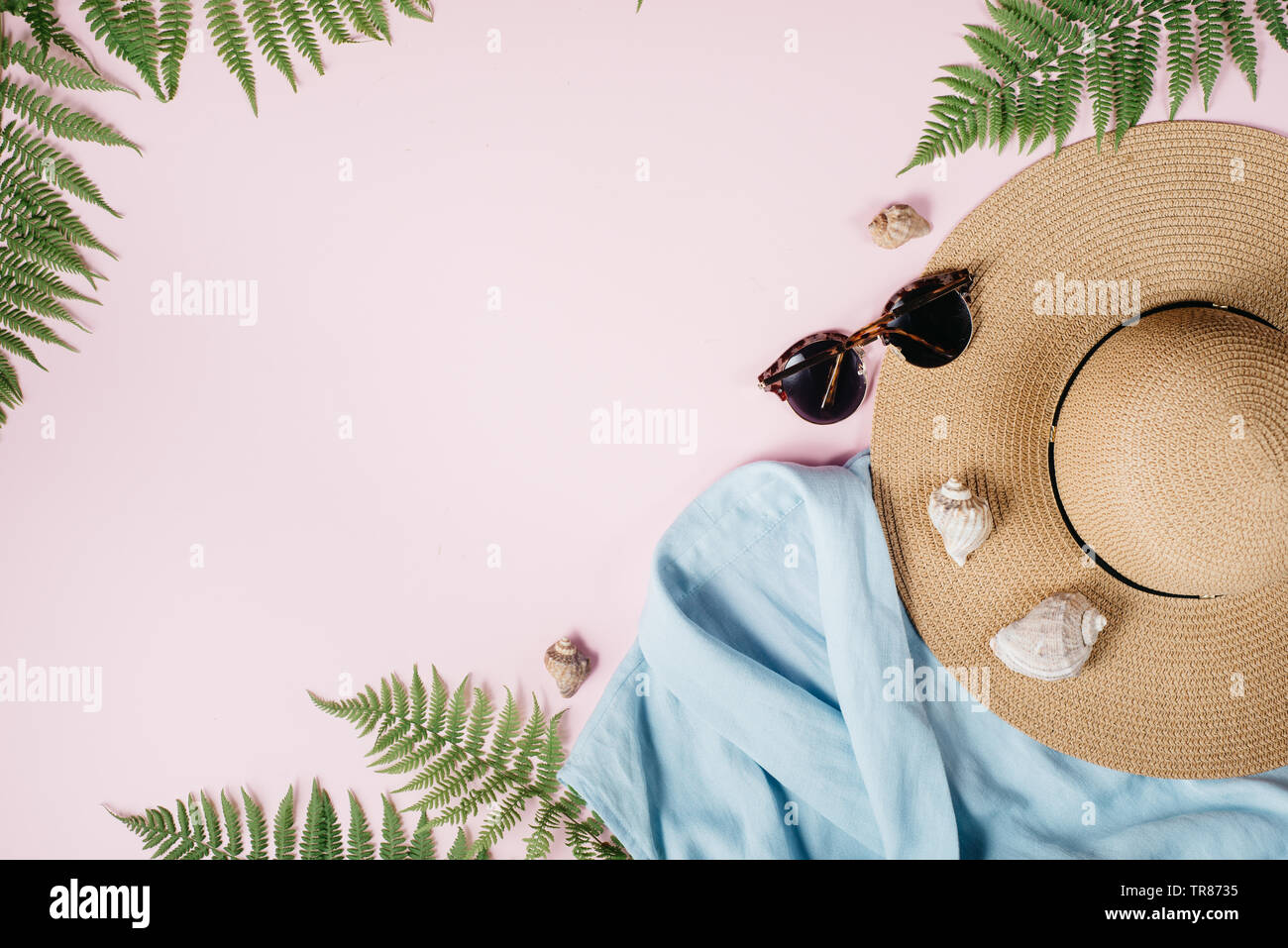 @Summer mode féminine composition avec un chemisier, chapeau, lunettes, fougère, seashell sur fond rose. Mise à plat, vue du dessus des vêtements minimalistes collage. Tr Banque D'Images