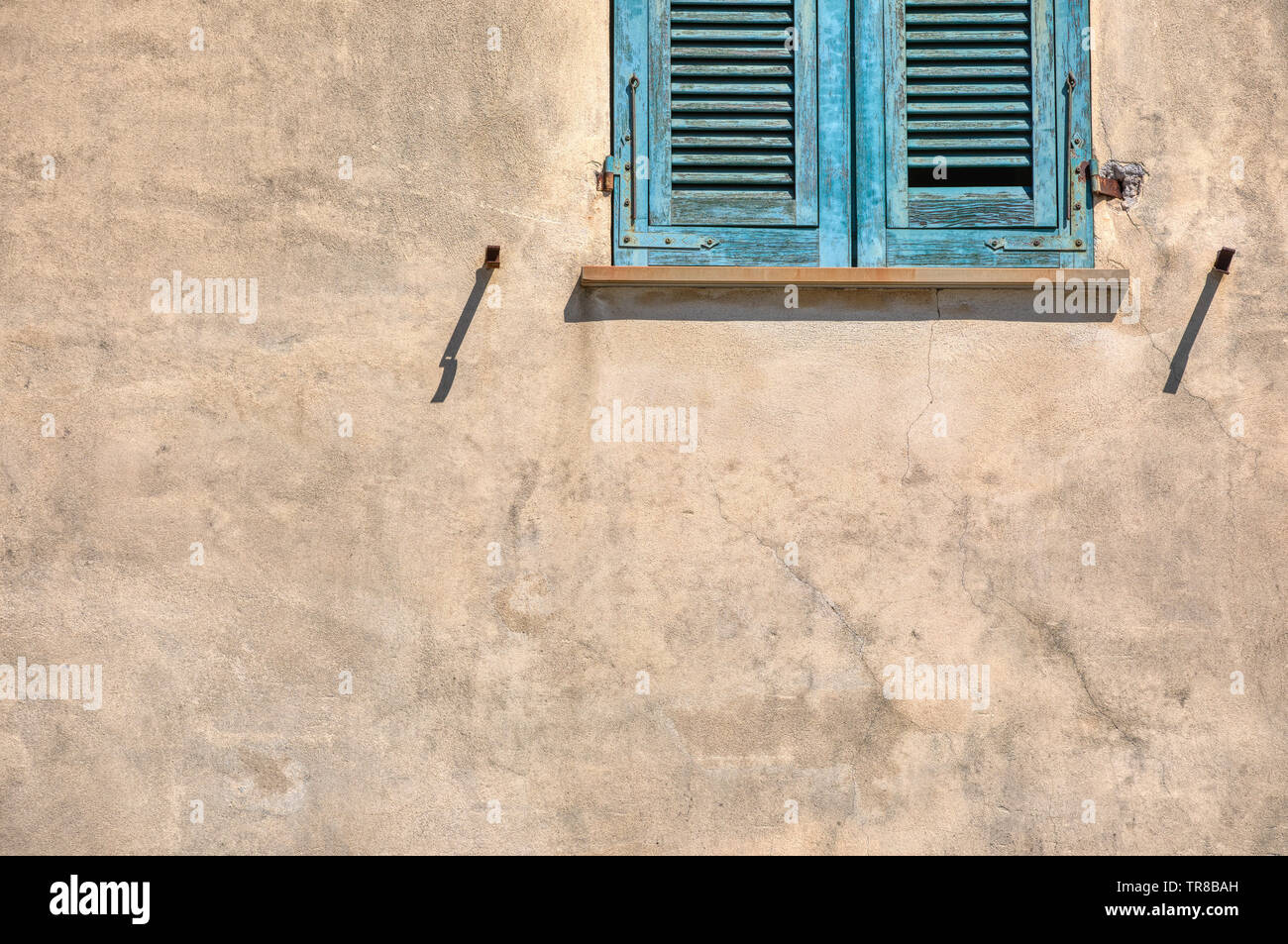 Photographie d'un lone érodés, volets vert contre un mur jaune pâle plater. Pris dans Cinque Terre Italie. Banque D'Images