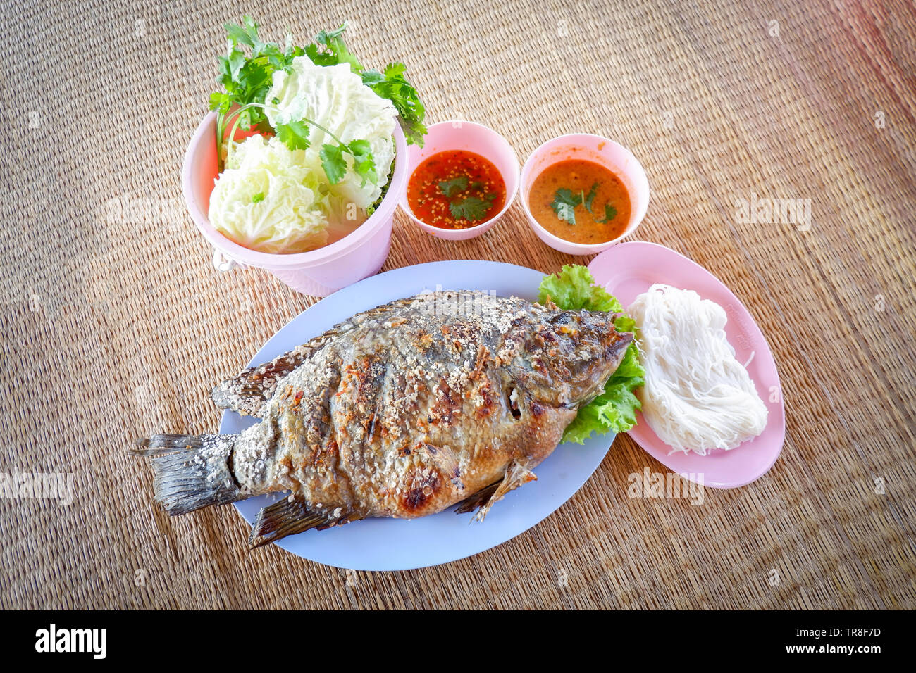 Jeu de poisson Tilapia grillé avec du sel et sauce chili de légumes frais dans un style thaï asiatique sur la plaque alimentaire poissons / brûler Banque D'Images