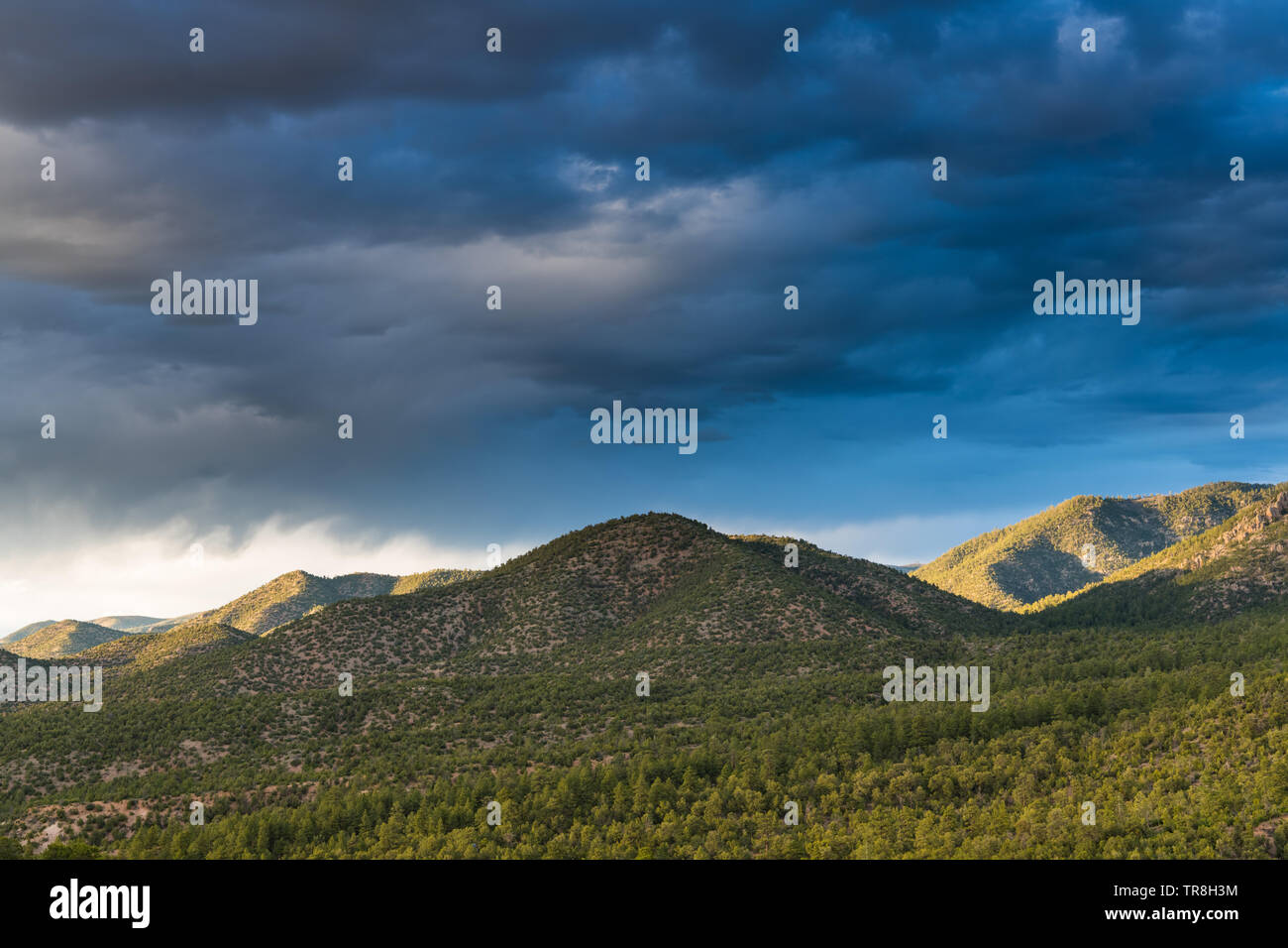Coucher du soleil illumine les collines et les montagnes sous un ciel dramatique de sombres nuages - les montagnes Sangre de Cristo près de Santa Fe, Nouveau Mexique Banque D'Images