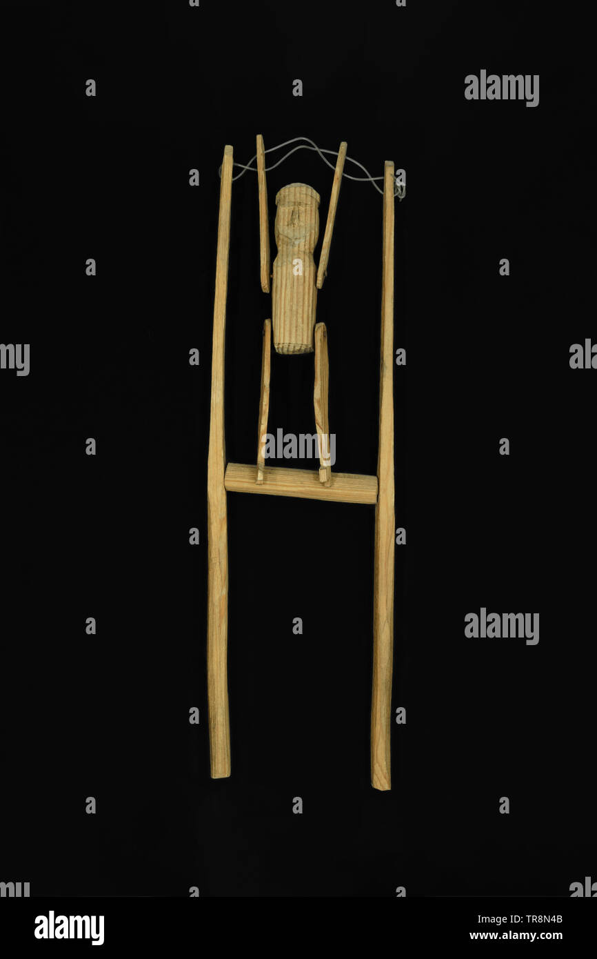 Vieux et rebondissant artisanal en bois jouet figurine forme humain isolé sur fond noir Banque D'Images