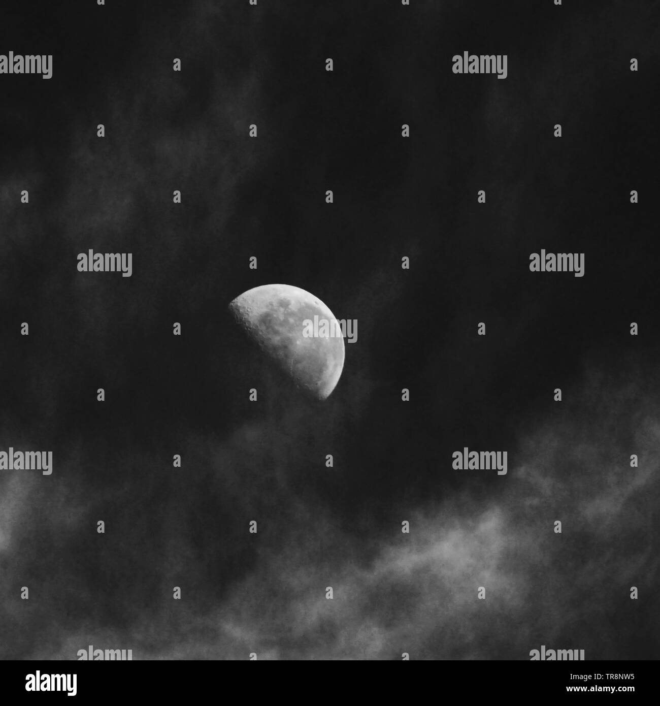 Eirerie noir et blanc de la Lune dans la journée entouré par des nuages blancs wispy, monochrome, surréaliste, ciel du sud de l'Australie Banque D'Images