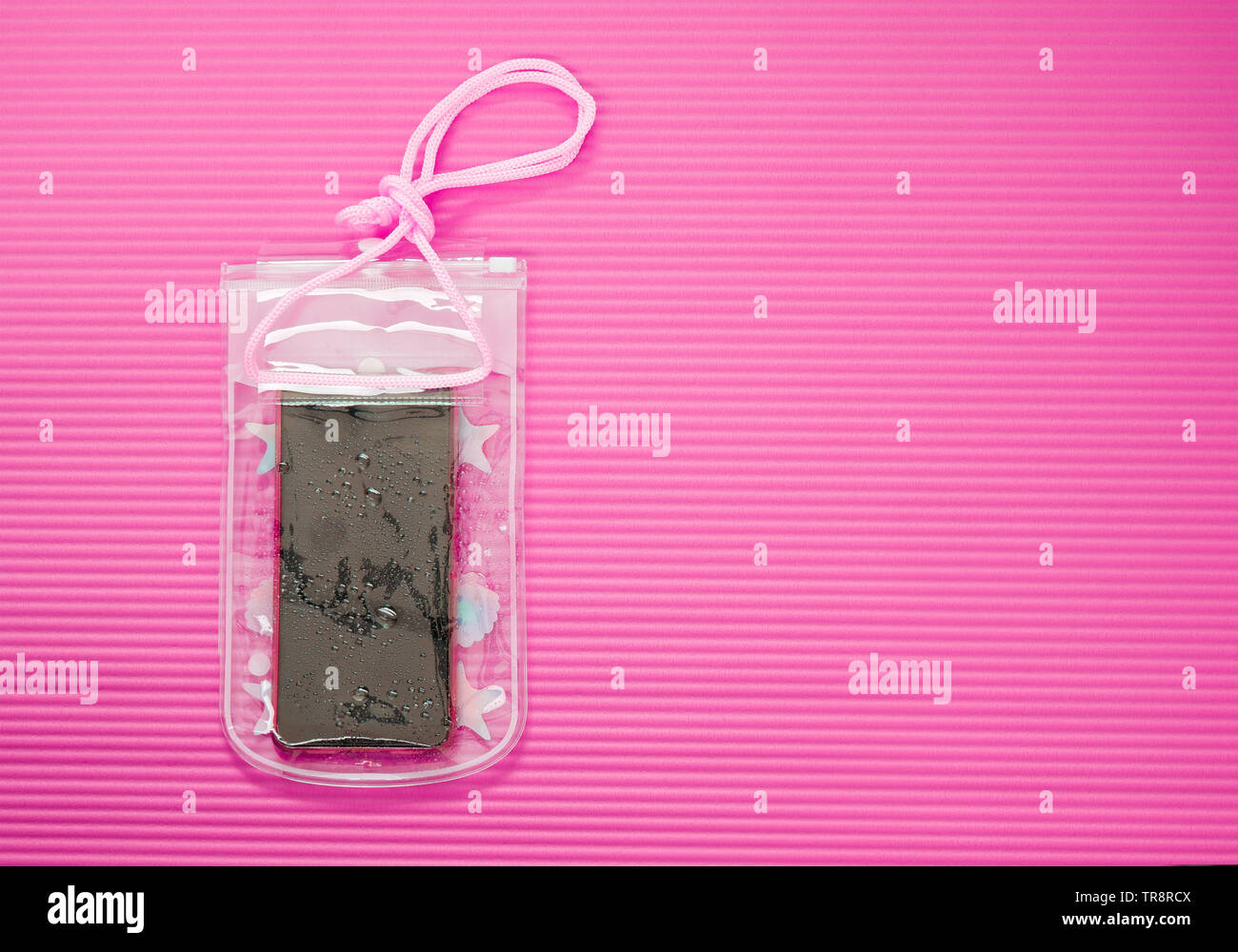 Téléphone portable étanche cas avec les gouttelettes d'eau isolé sur fond rose mat. PVC Plastique étanche pour Smartphone, sacs à fermeture ZIP Protéger. Banque D'Images