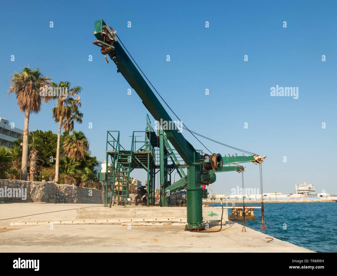Ancien mécanisme de levage treuil sur l'embarcadère en béton de la mer, des palmiers et de la mer. Banque D'Images