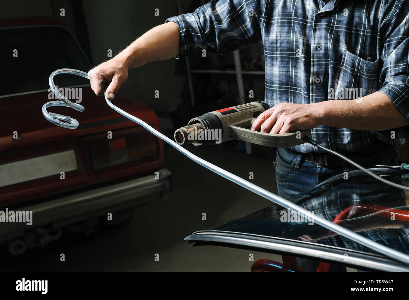 Mécanicien automobile est holding Hot Gun et le réchauffement d'une moulure décorative pour une installation facile. Banque D'Images
