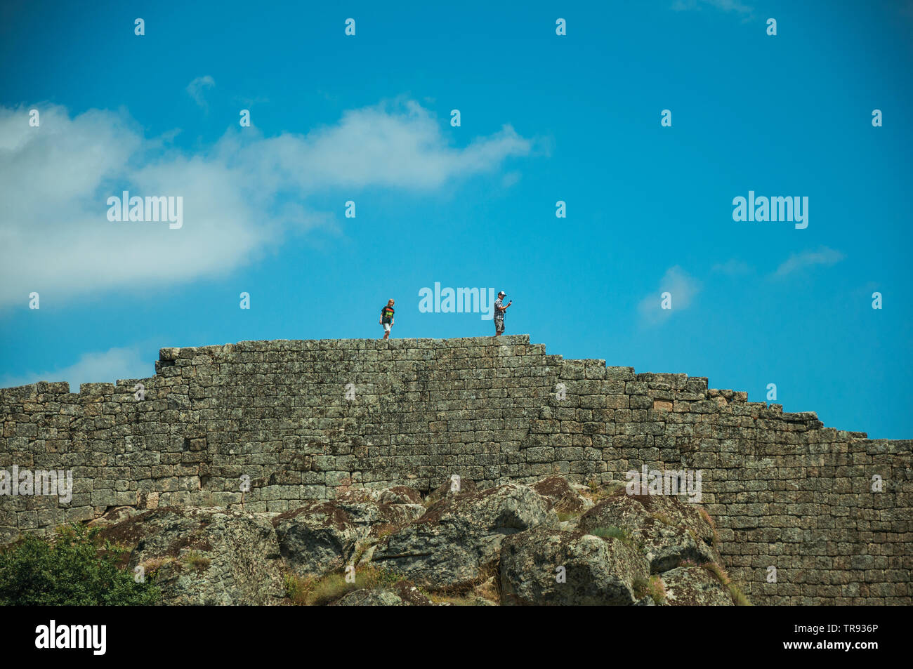 Les gens qui passent à travers un sentier sur grand mur de pierre en Sortelha. Une étonnante et bien préservé de hameau médiéval au Portugal. Banque D'Images