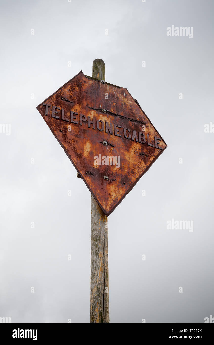 Câble téléphonique. Navire endommagé grunge navigation sur poteau de métal sous ciel nuageux gris Banque D'Images