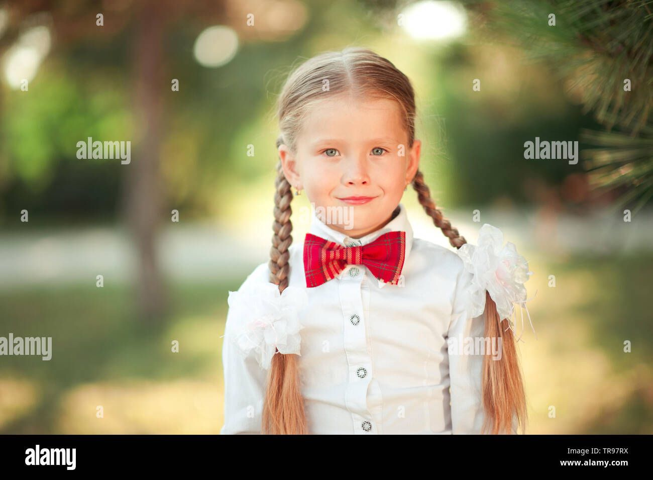 Fille enfant 6-7 ans smiling outdoors. Portant chemise blanche et cravate  rouge. En regardant la caméra Photo Stock - Alamy