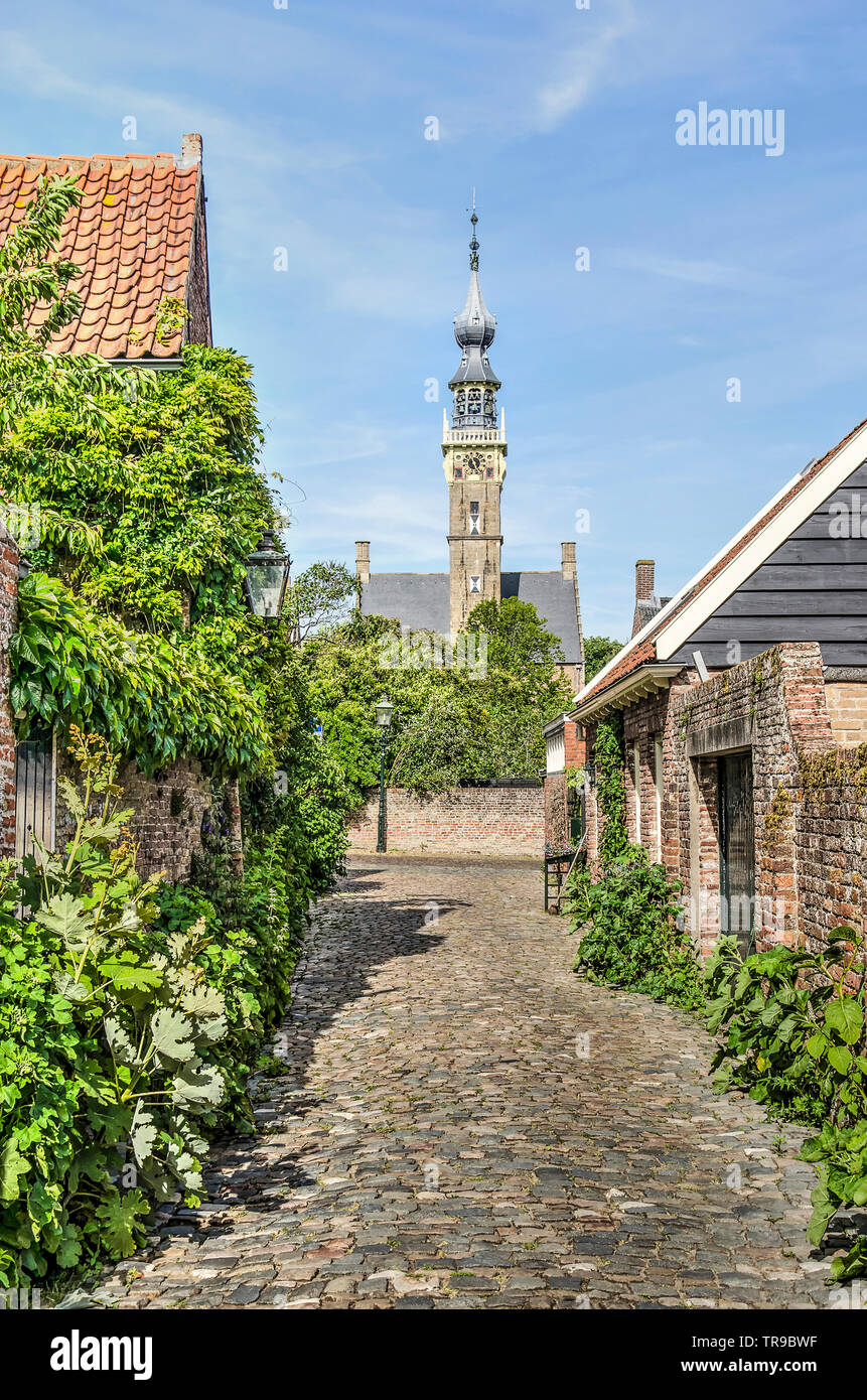 Dordrecht, Pays-Bas, Mai 30, 2019 : voir à travers une ruelle étroite pavée de pierres et de galets bordée de jardins et de maisons, vers la tour de la Banque D'Images