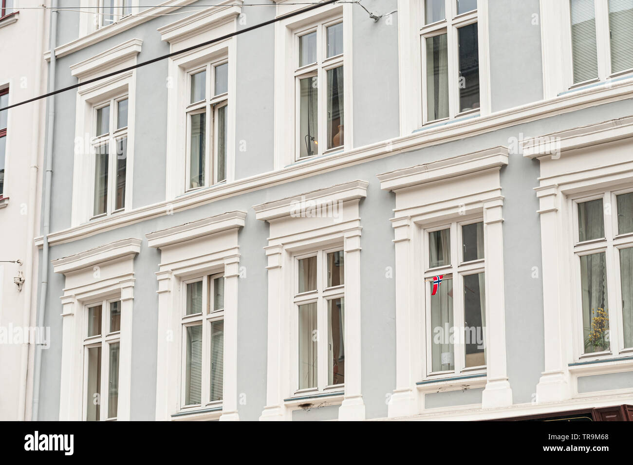 Façade avec fenêtres sur un bâtiment bleu. Un seul, petit pavillon norvégien dans une des fenêtres. Banque D'Images