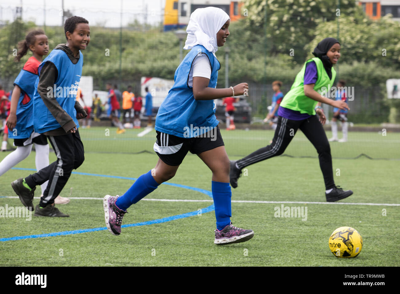 Les filles musulmanes jouent au football sur un terrain d'entraînement astroturf. Certains portent un hijab (foulard). Banque D'Images