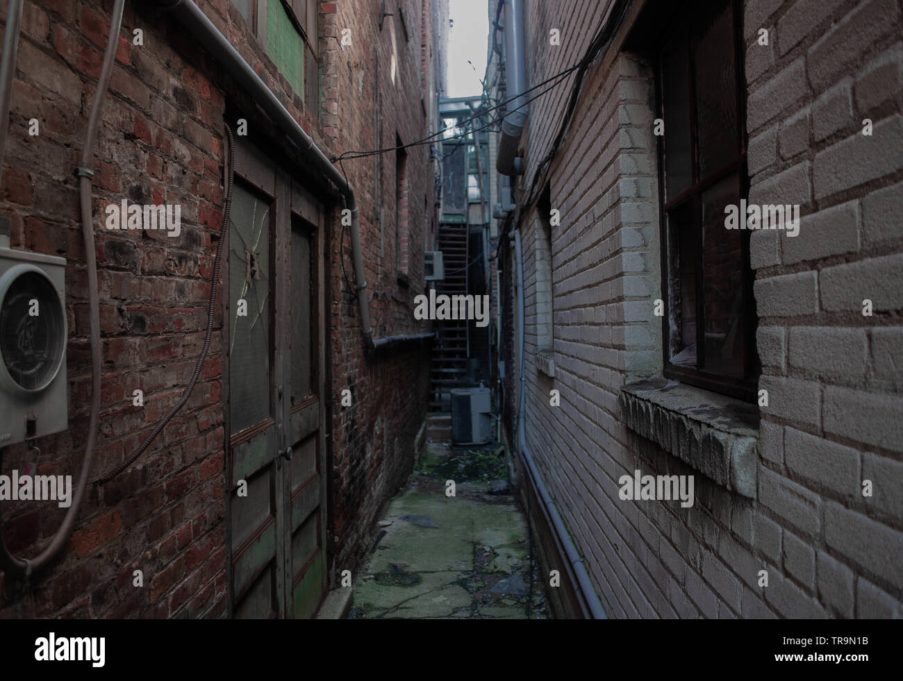 Old alley avec des briques fissurées et les fenêtres brisées. Banque D'Images