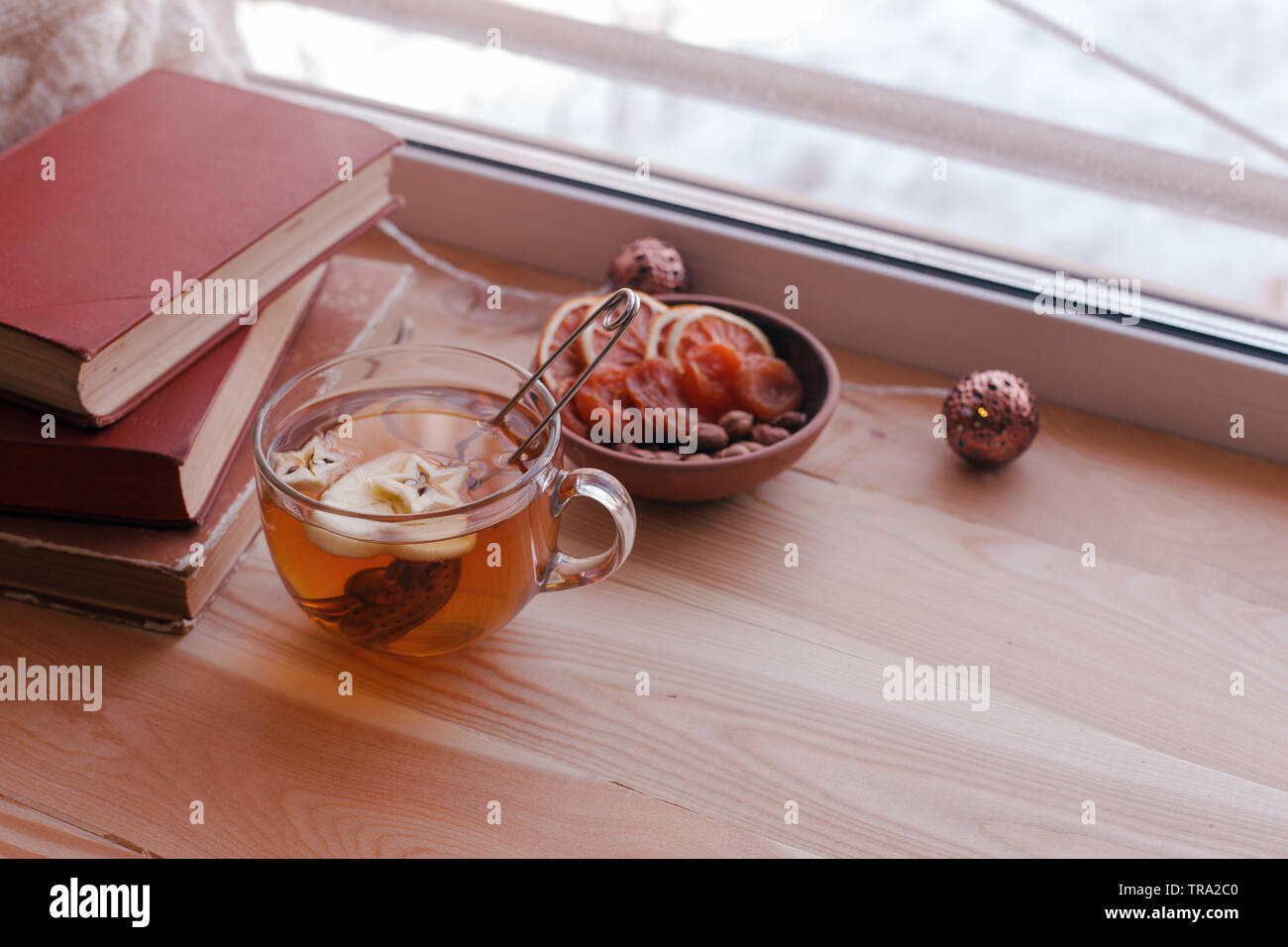 Concept d'automne chaudes et confortables. Livre, tasse de thé sur appui de fenêtre dans la chambre. La lecture et de détente par temps froid à la maison. Le silence paisible scène familiale. Mono Banque D'Images
